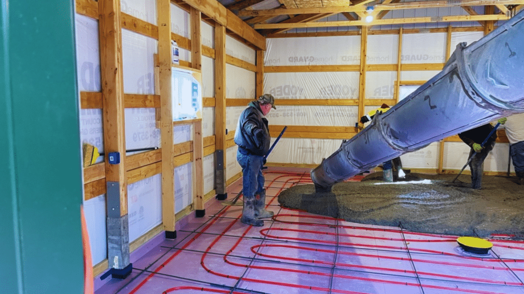 workers installing radiant floor heating pipes and pouring concrete over them