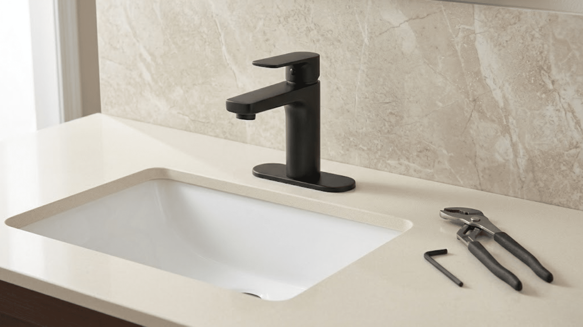 a matte black faucet and plumbing tools on a bathroom countertop with a marble backsplash