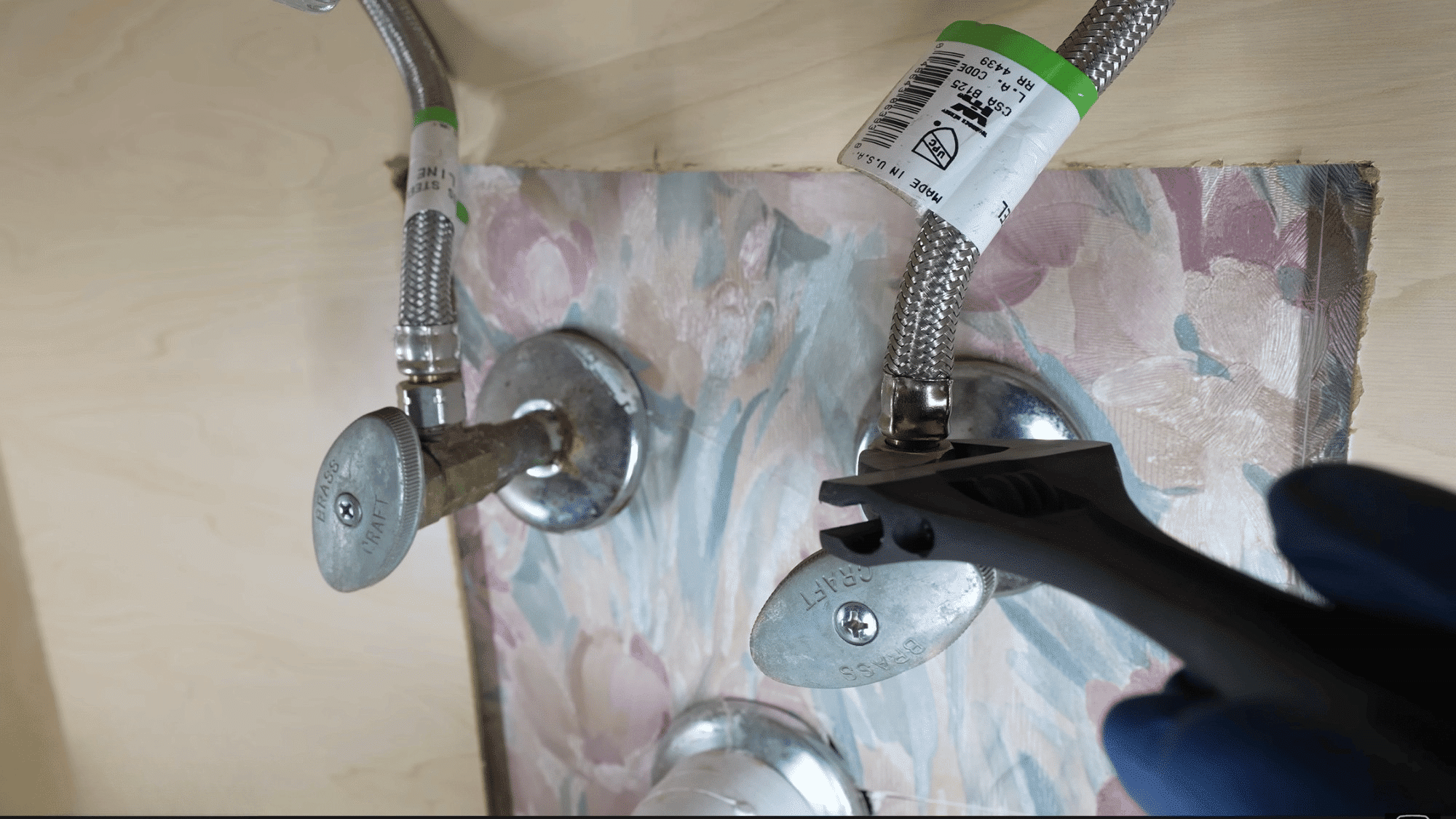 adjustable wrench loosening water supply line connection beneath bathroom sink during faucet replacement