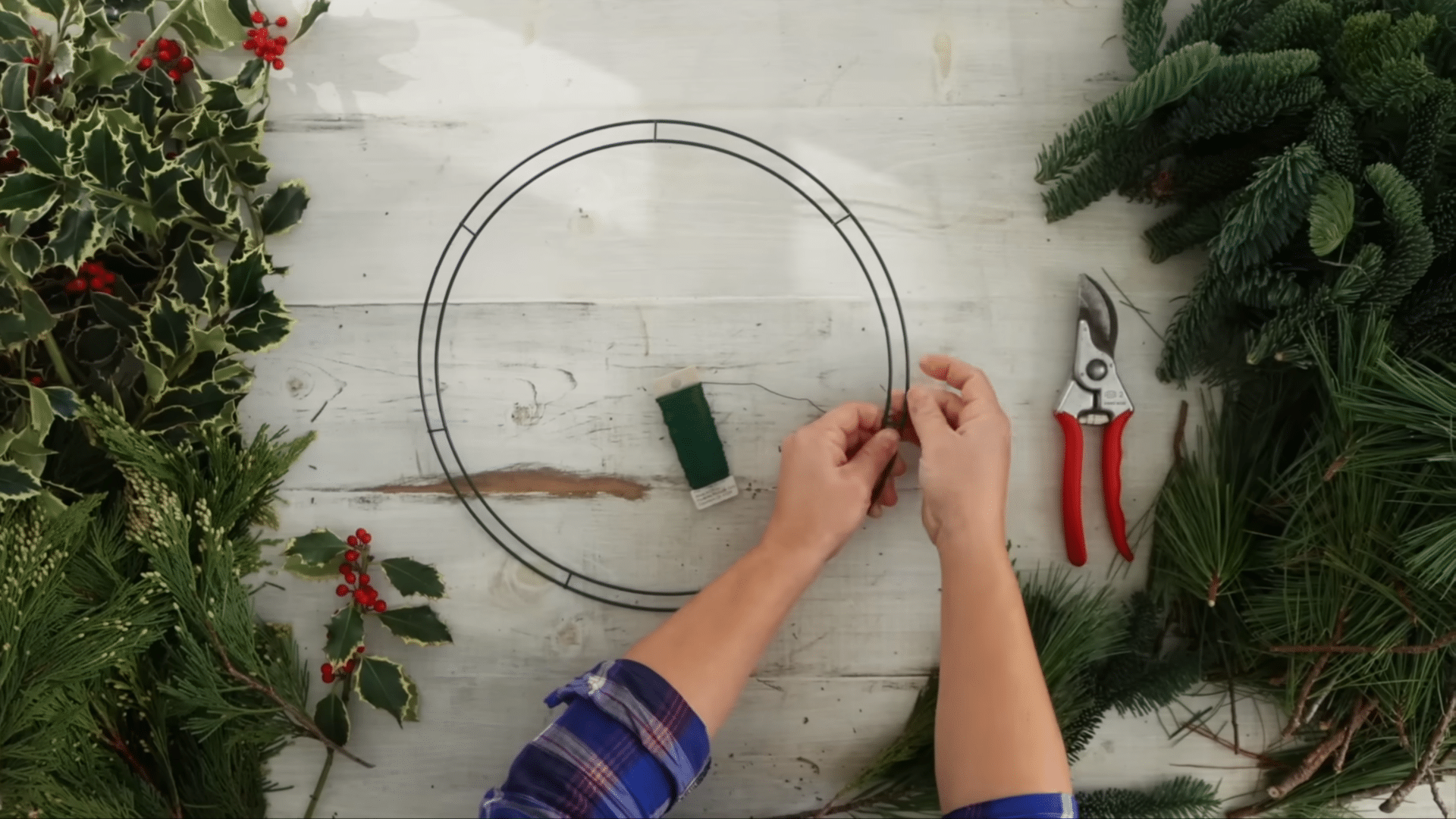 attaching paddle wire tightly to the wreath frame to create a secure base for the greenery