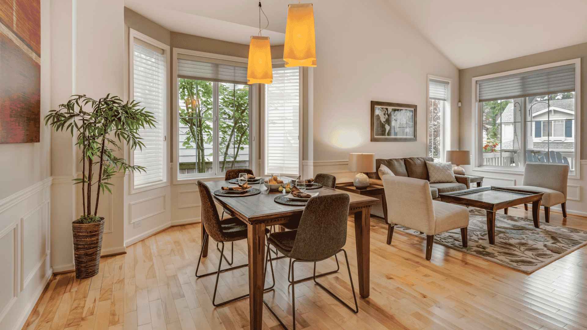 bright dining and living room with wood flooring large windows pendant lights and neutral furnishings