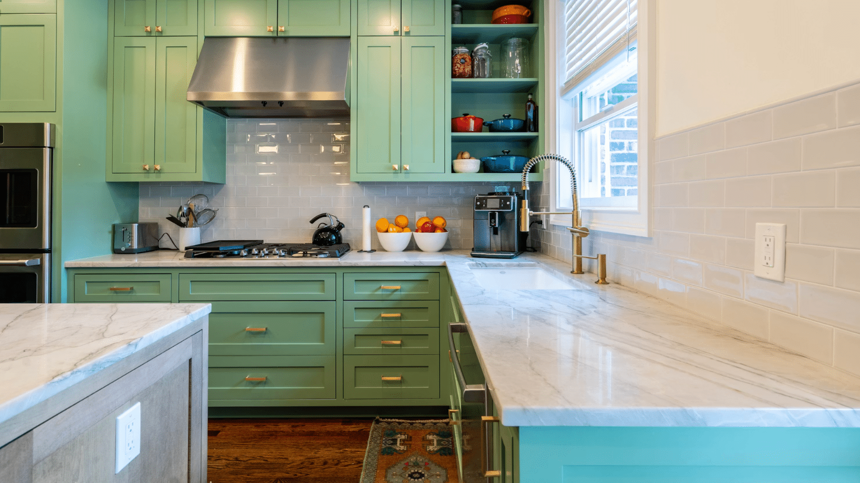 bright kitchen with sage green cabinets marble countertops open shelving and stainless steel range hood