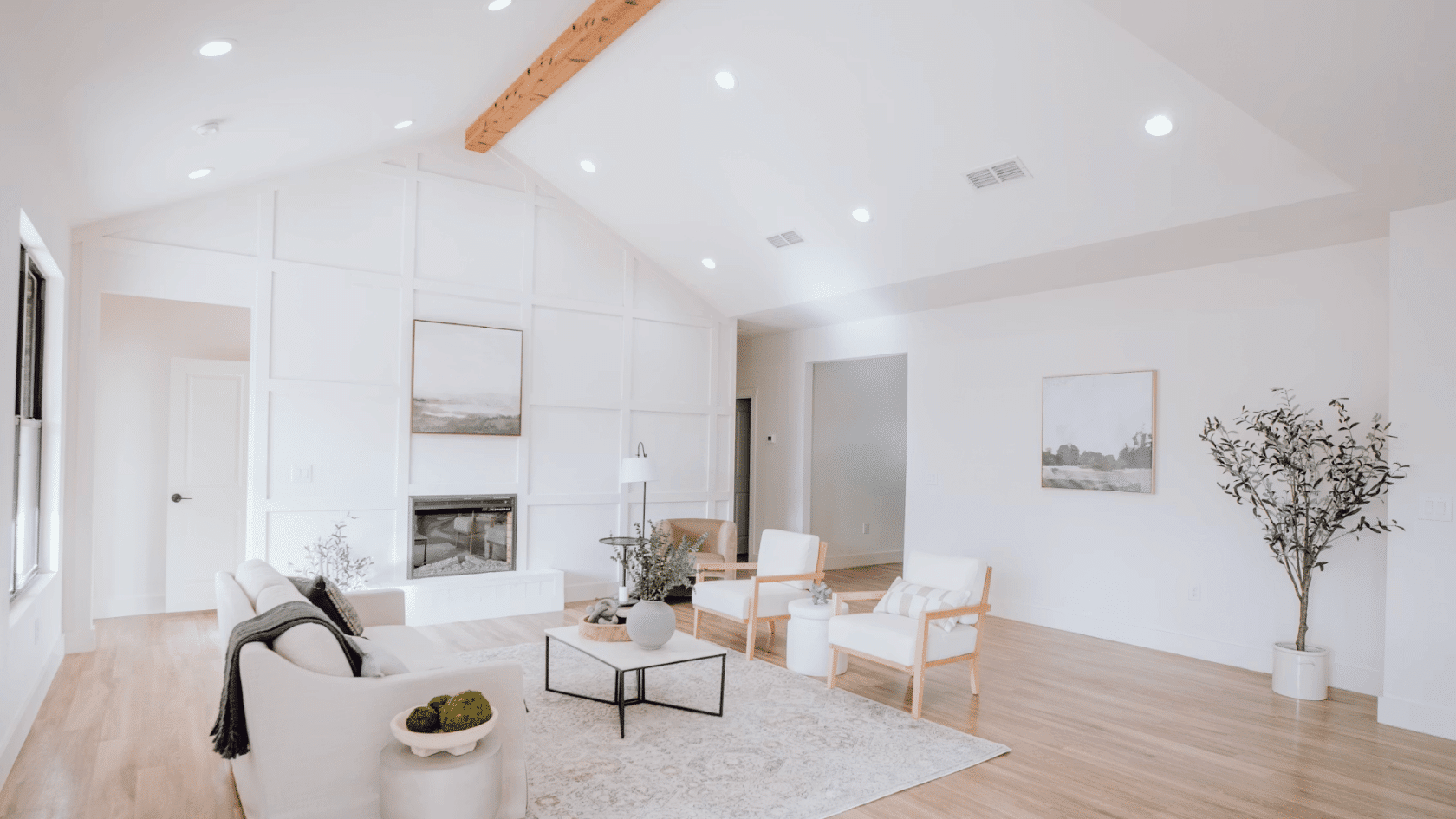 Bright modern living room with vaulted ceiling recessed lighting white walls and light wood flooring