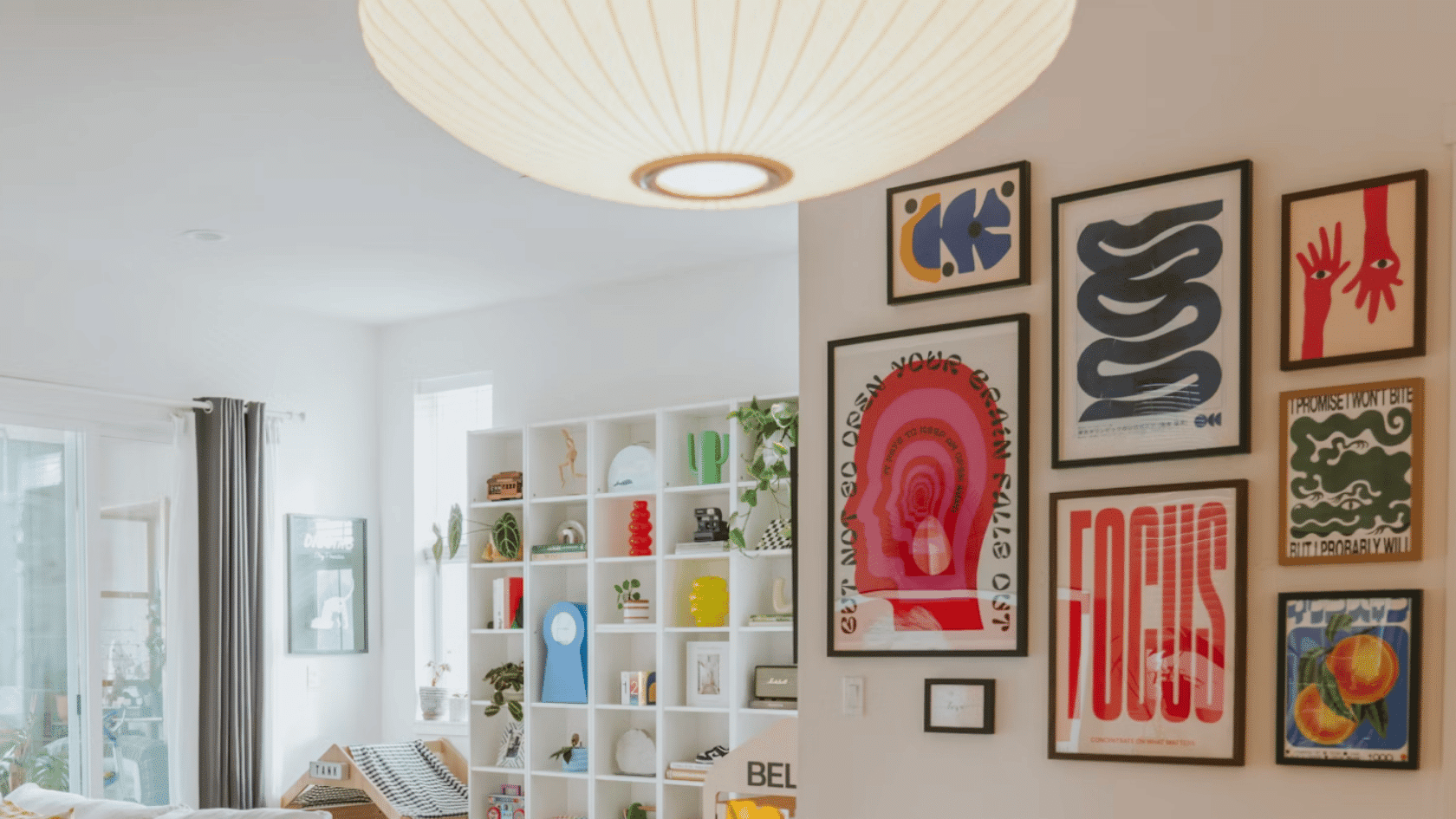 bright modern living space with colorful framed artwork white shelving and decorative objects against a light wall