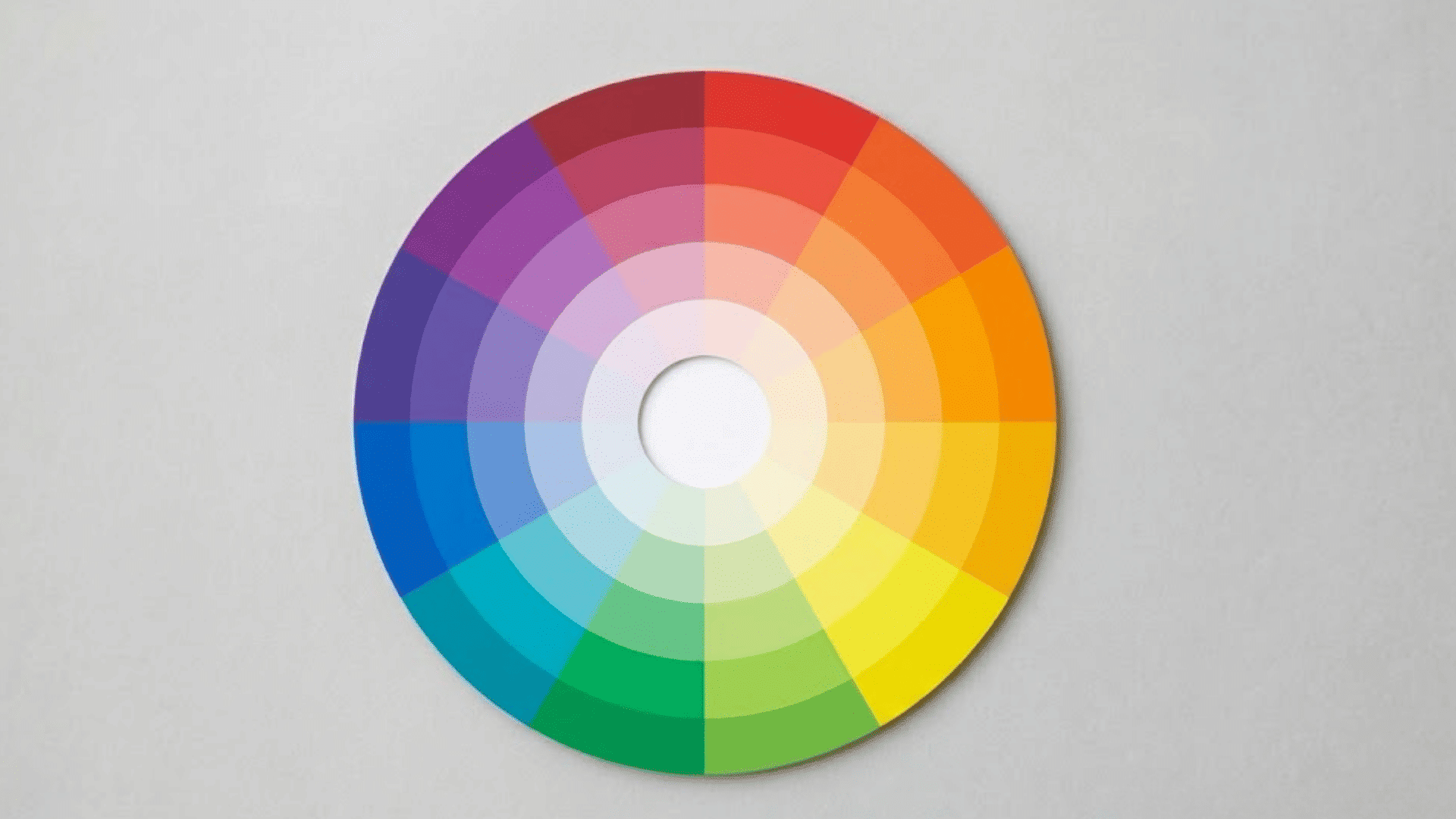 circular color wheel showing gradients from warm to cool hues arranged in segmented rings on a gray background