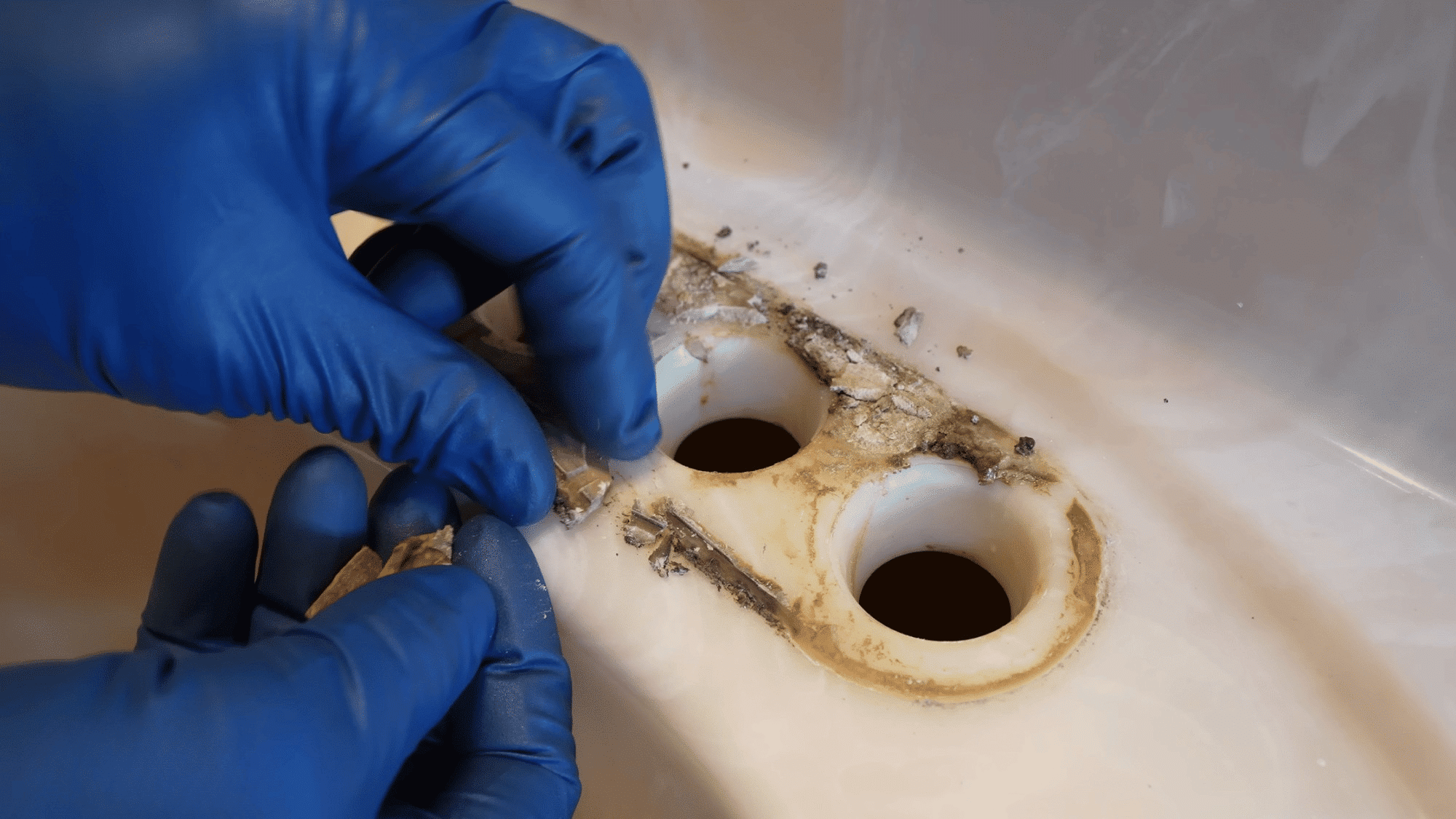 cleaning old sealant and debris from sink faucet holes before installing a new bathroom faucet