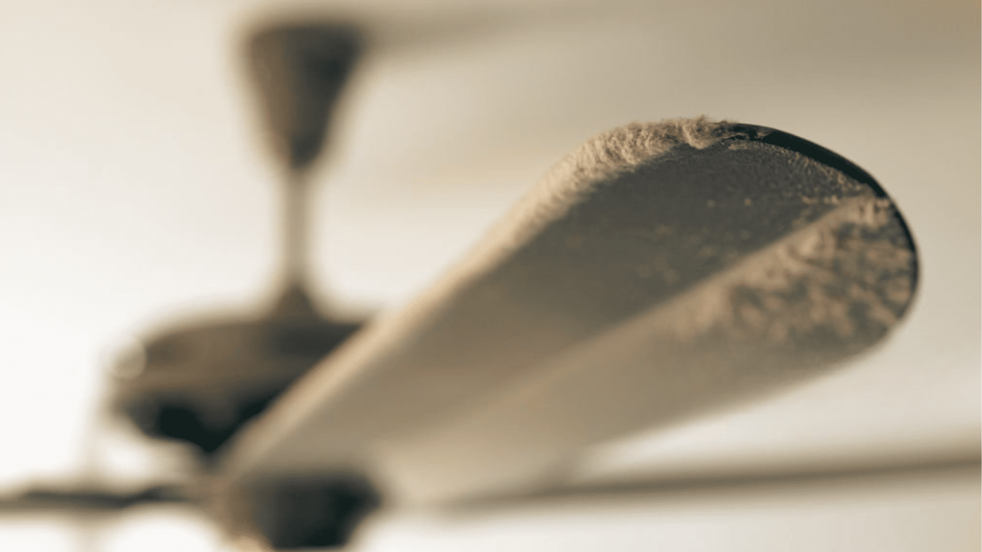 Close-up of a dusty ceiling fan with heavy dust buildup blocking airflow.