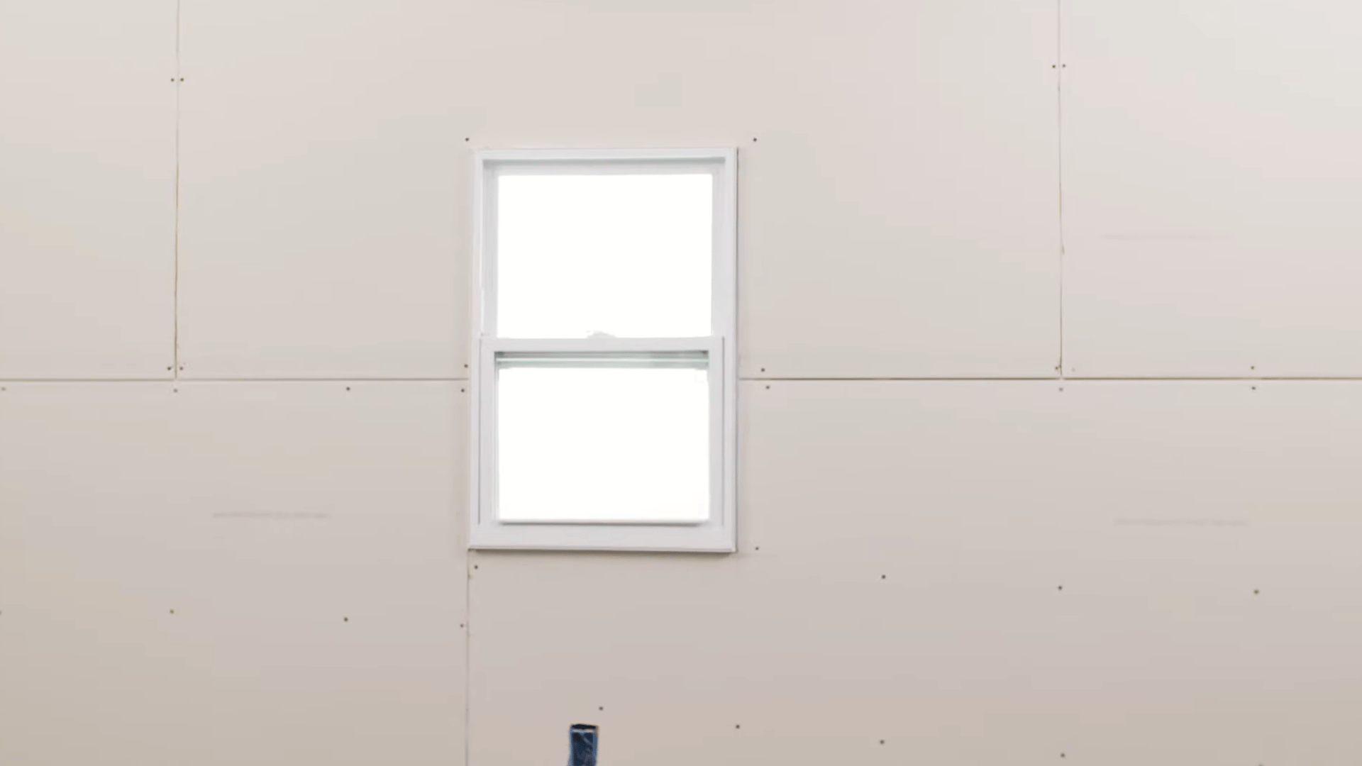 completed drywall wall installation with a finished window opening and securely fastened panels ready for taping and finishing