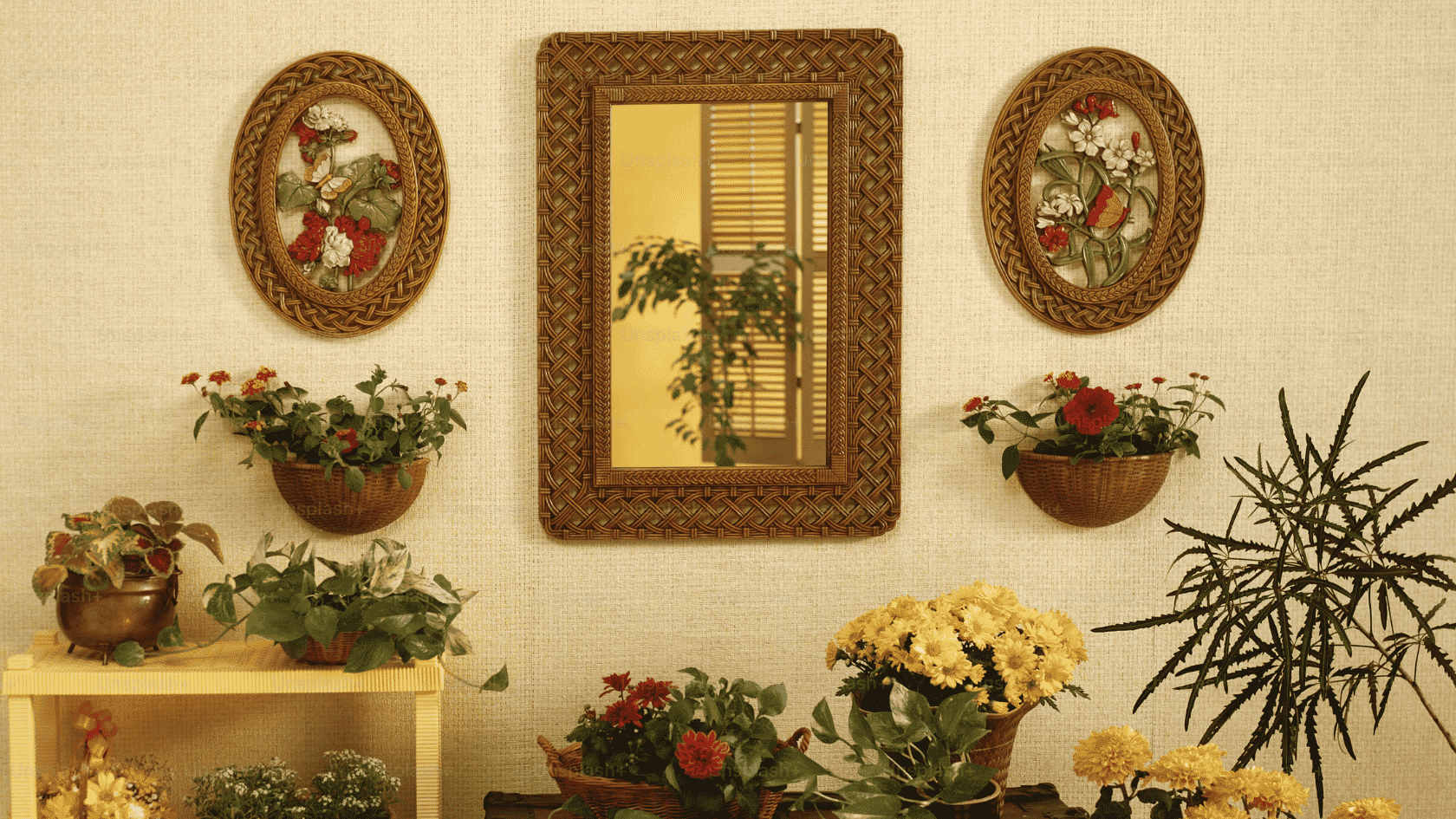 decorative wall with woven framed mirror floral artwork and potted flowering plants arranged in a cozy display (1)