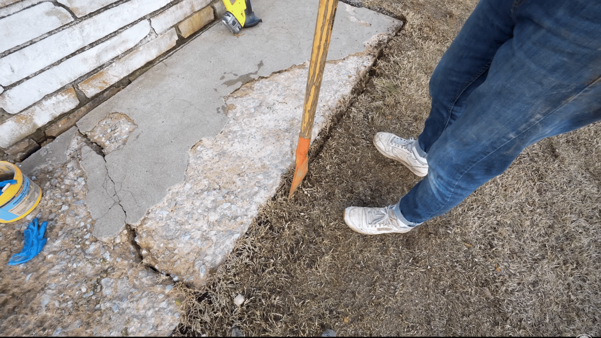 digging along the edge of a spalled concrete slab to prepare the surface for patching and resurfacing