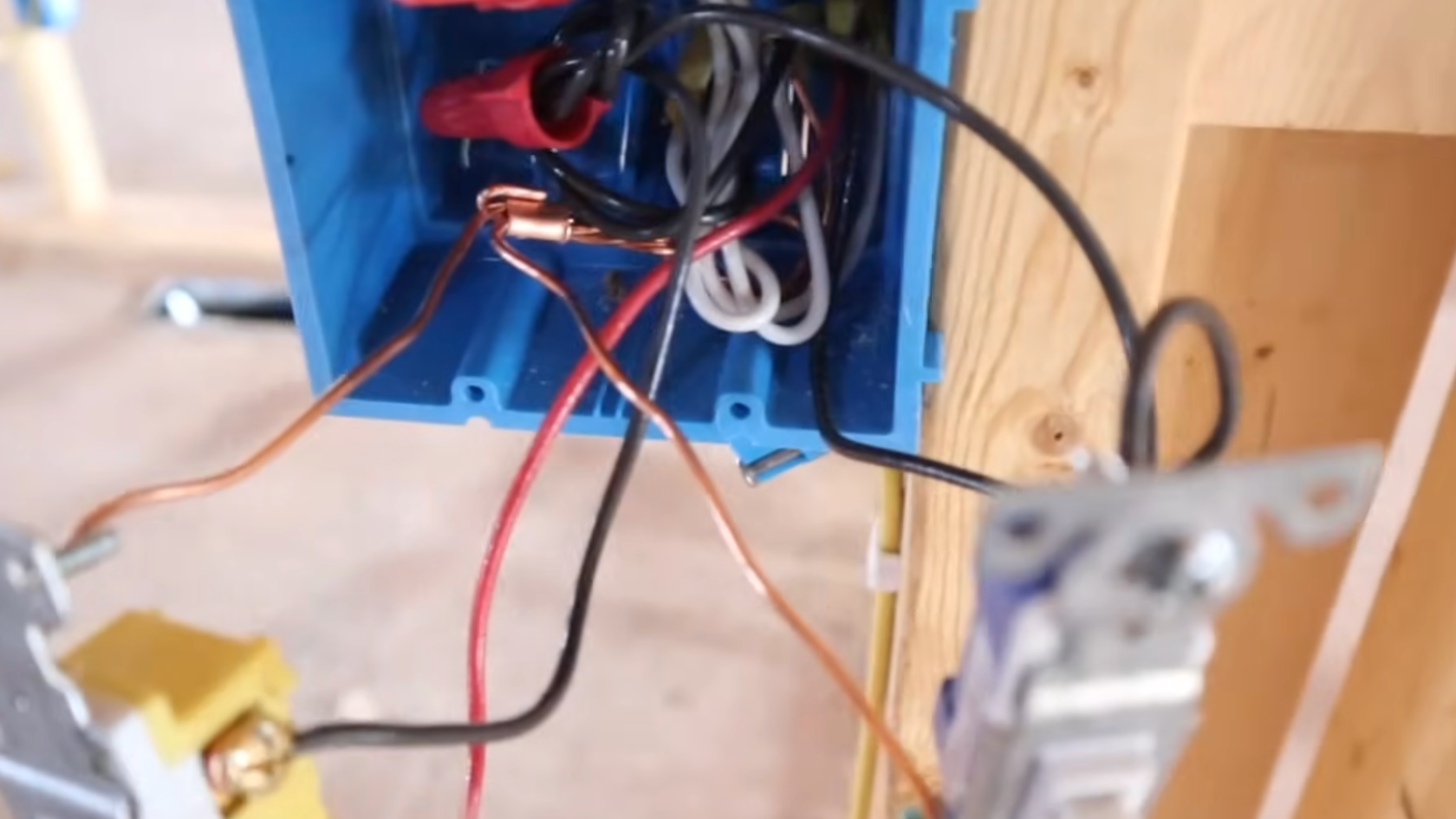 electrical wires connected inside a blue junction box with a switch hanging outside during residential wiring installation