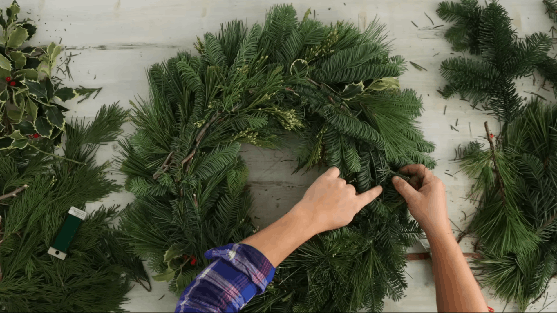 filling the final gap with extra evergreen pieces and berries for a complete wreath look (1)