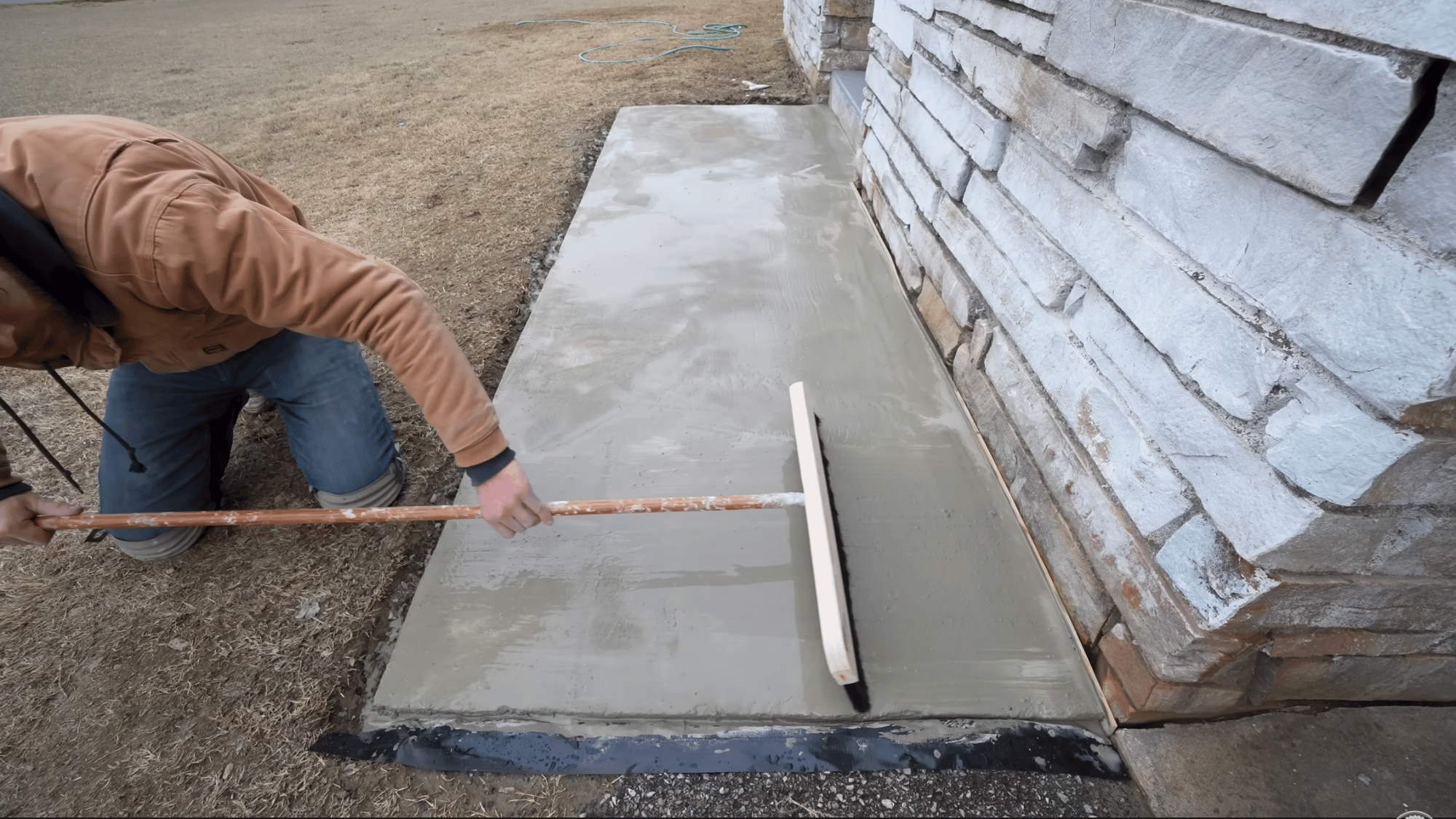 finishing fresh concrete resurfacer with a broom to smooth the surface and improve texture