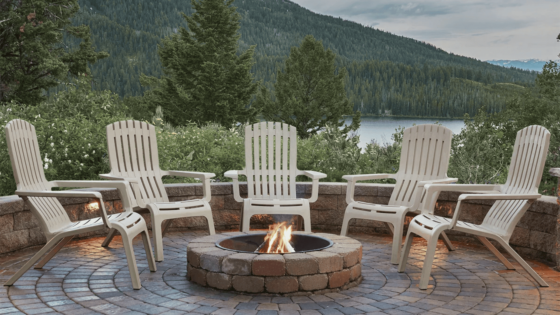 gravel patio ideas with a fire pit and circular stone layout surrounded by white chairs for a scenic outdoor retreat