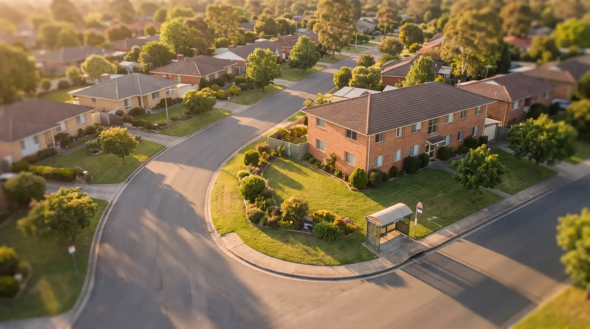 Aerial view of a residential street mixing single-family homes and a small apartment building in a suburban neighbourhood.