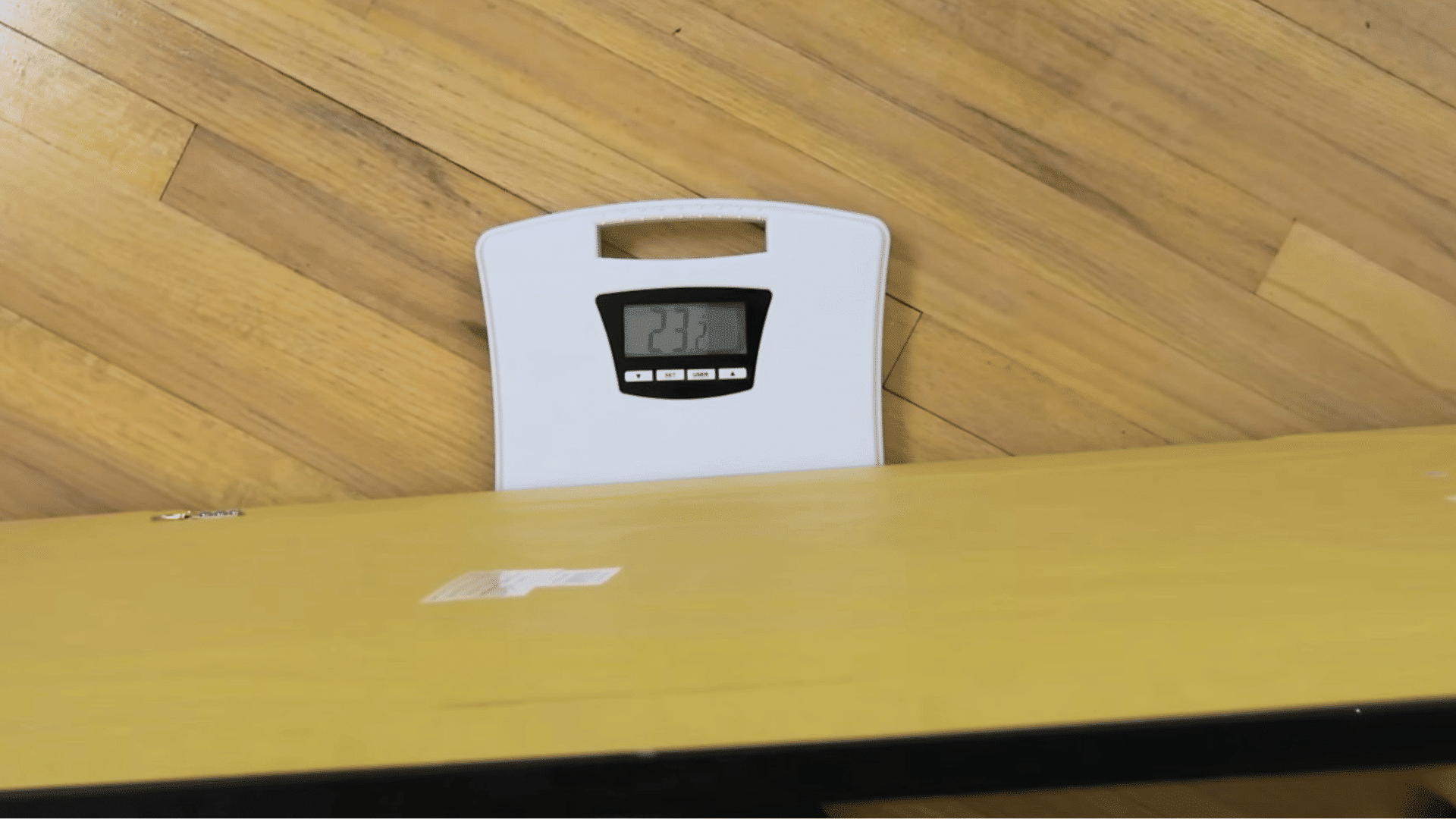 large framed picture resting on a digital scale on a hardwood floor to measure weight before wall mounting installation