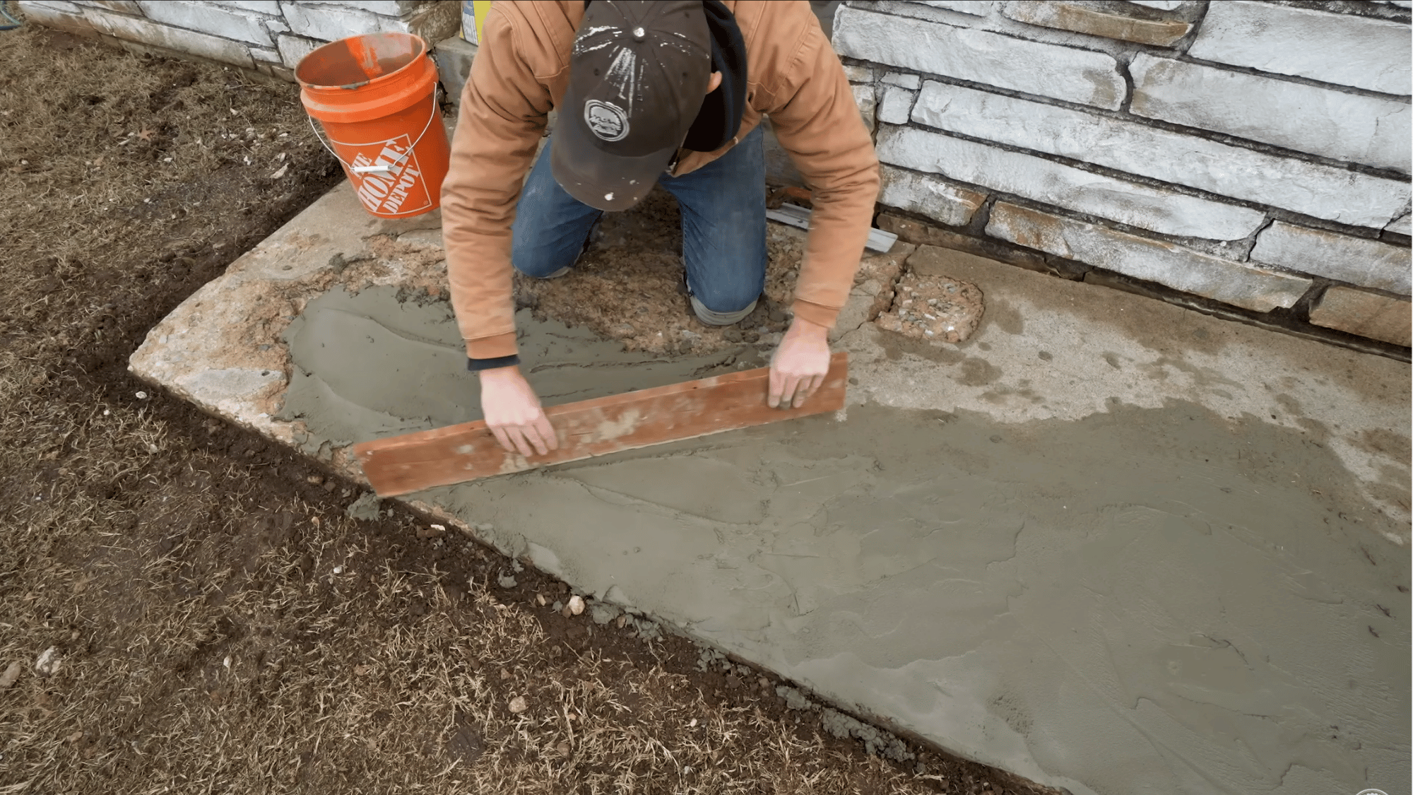 leveling freshly applied concrete patch with a straight board to create an even repair surface