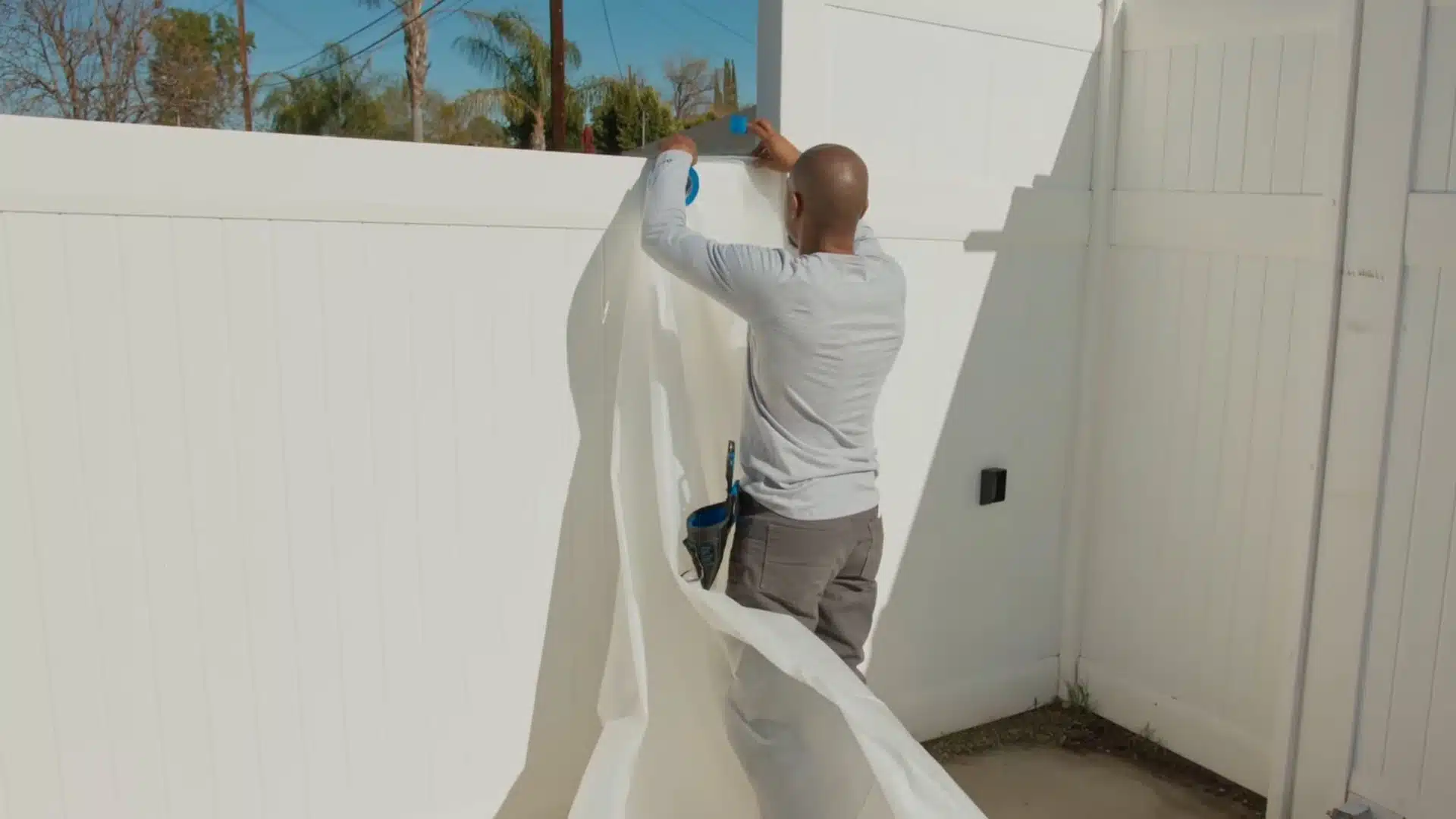 Driveway perimeter covered with plastic and tape to protect plants, walls, and edges from stain