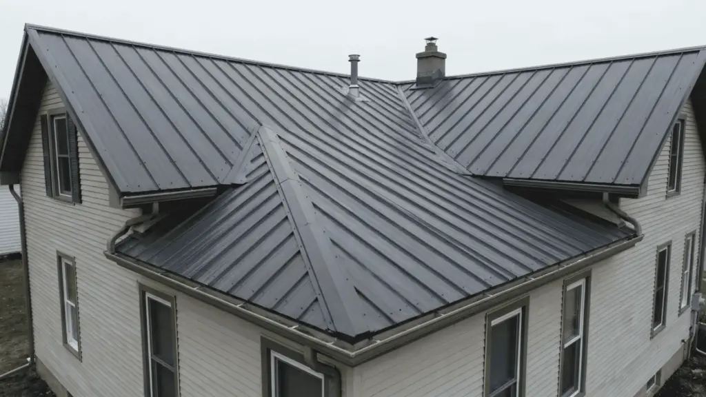 wide view of house with gray standing seam metal roof showing multiple roof sections and gutters on residential building