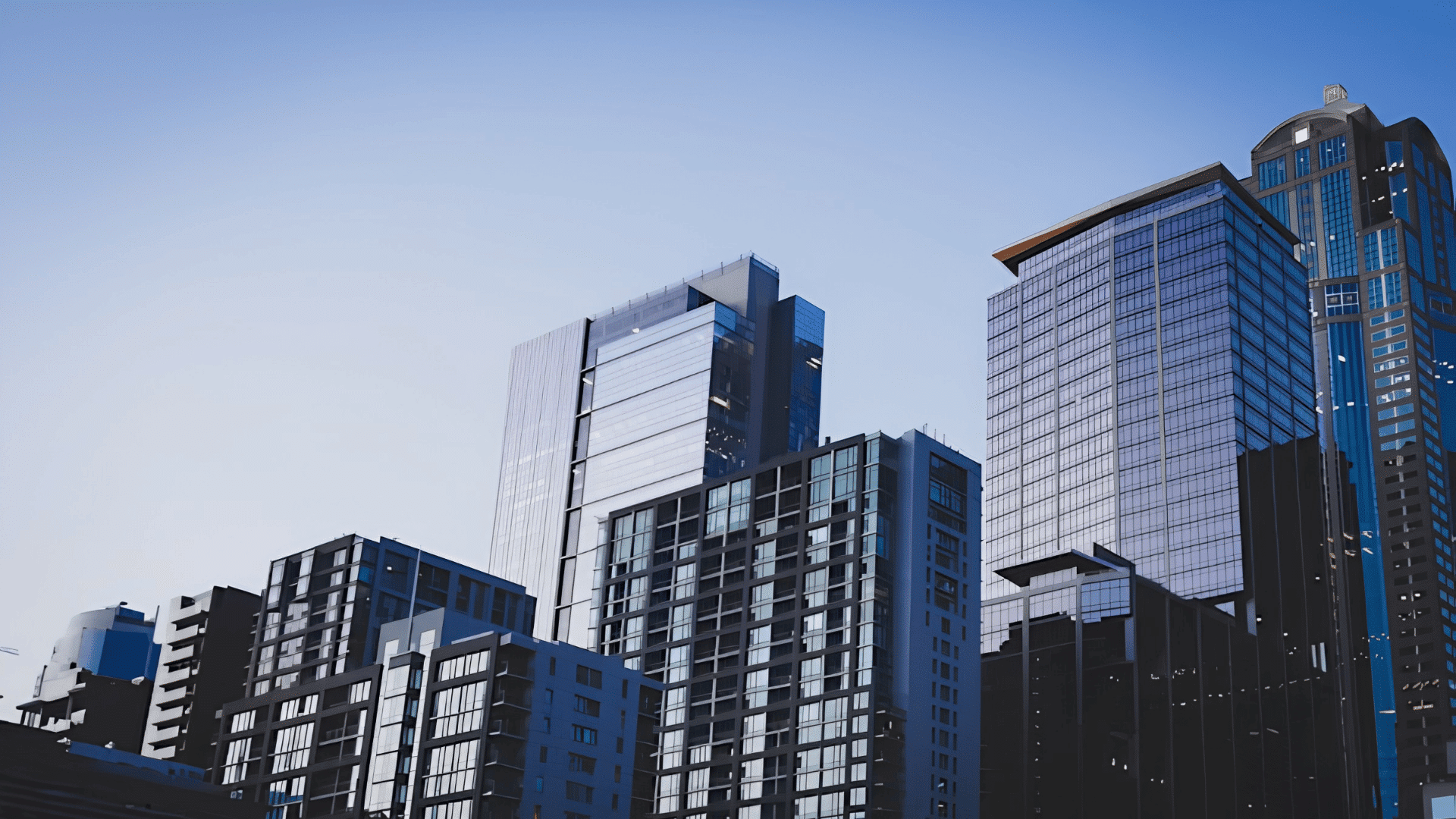 modern commercial real estate buildings with glass facades in a city business district under clear blue sky