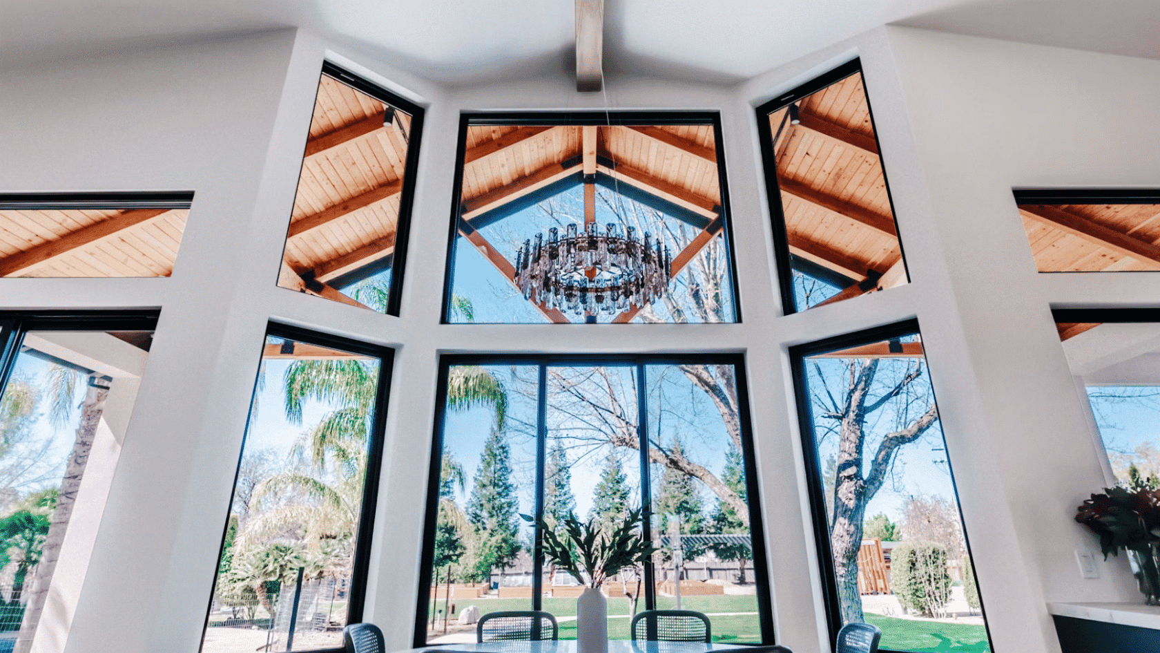 Modern dining area with floor to ceiling windows vaulted ceiling and garden views through black framed glass