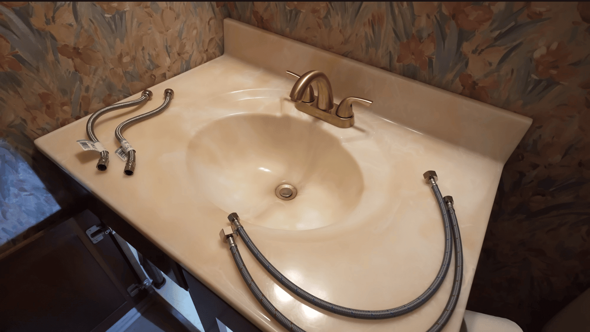 new bathroom faucet and supply lines arranged on countertop before installation begins