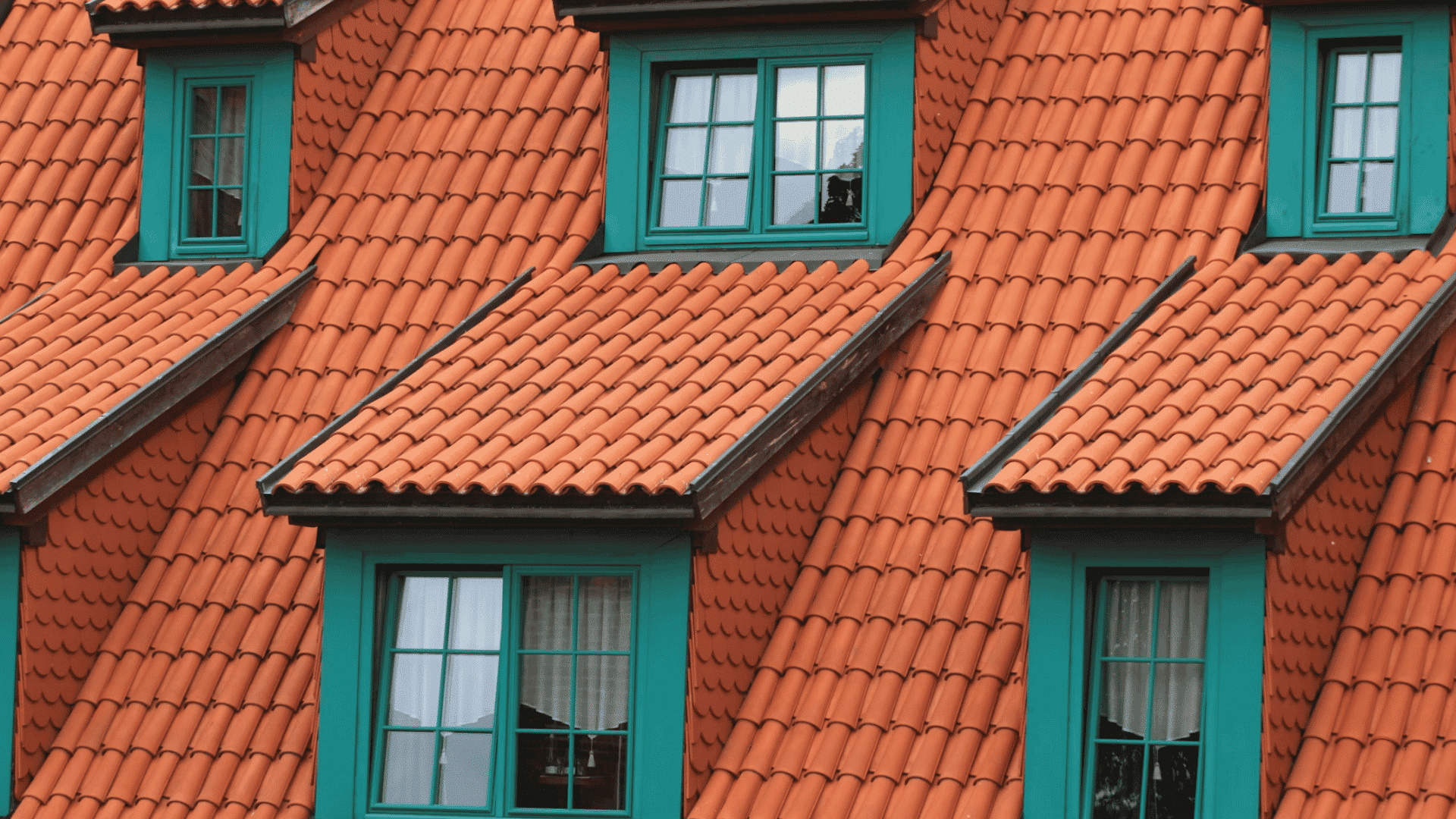 orange clay tile roof with green framed dormer windows arranged in a repeating geometric pattern