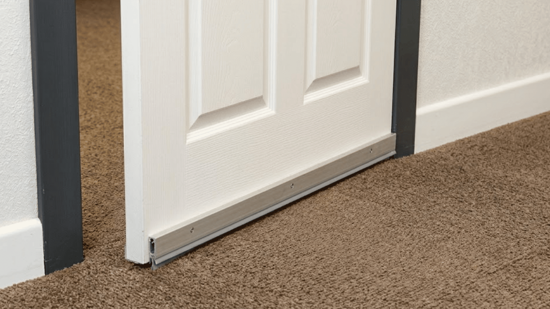 partially open white interior door with a metal threshold strip positioned above a beige carpeted floor surface