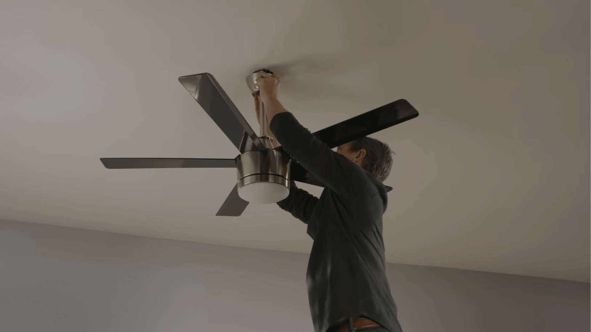 person installing a new ceiling fan as a replacement for an older unit with persistent wobbling or mechanical issues