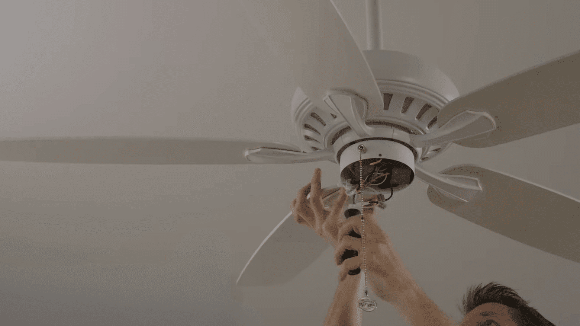 person replacing or adjusting ceiling fan blades to correct imbalance and ensure smooth stable operation during use