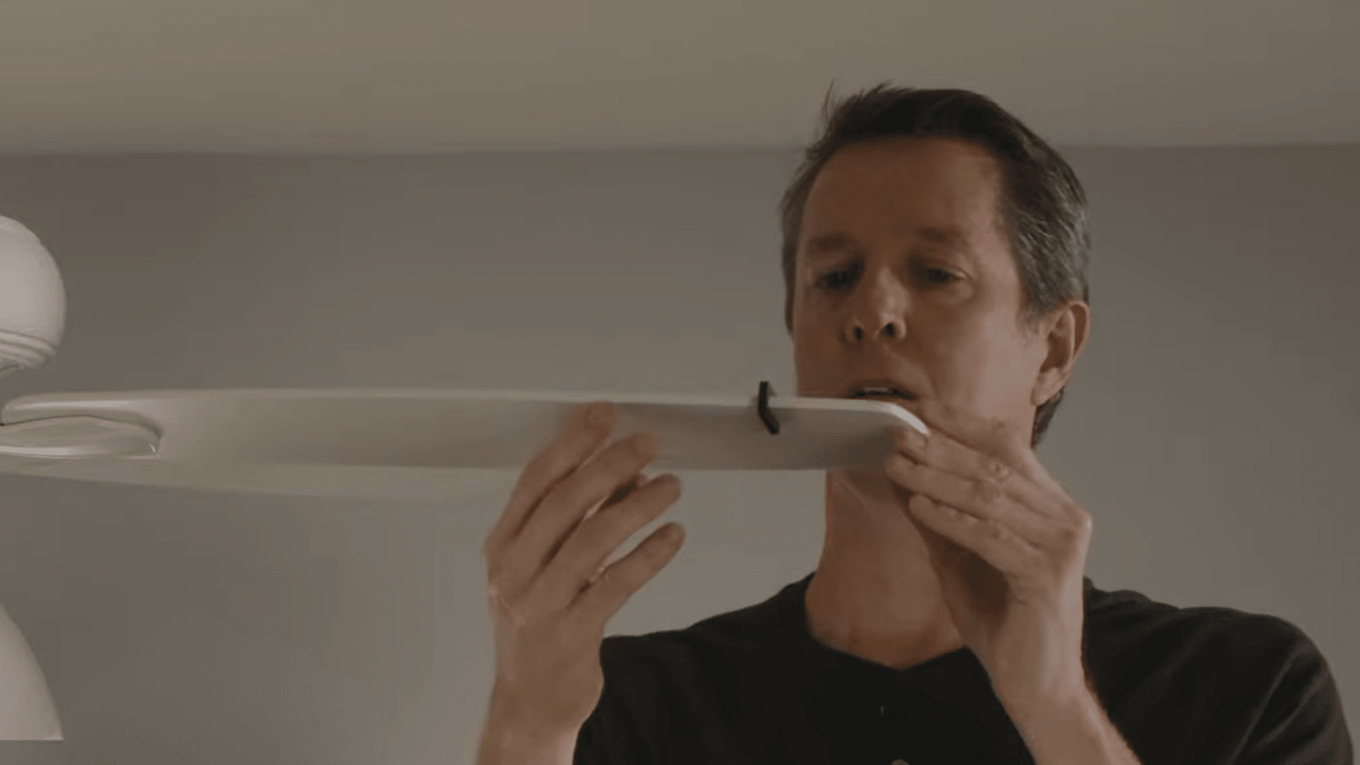 person testing a ceiling fan balancing clip on a blade to identify the source of wobble and improve stability