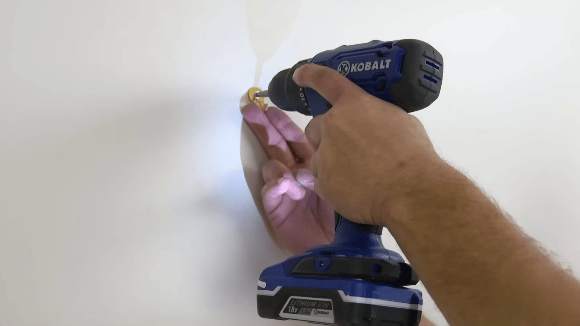 person using a cordless drill to fasten wall mounting hardware into a marked location for hanging a heavy mirror or picture