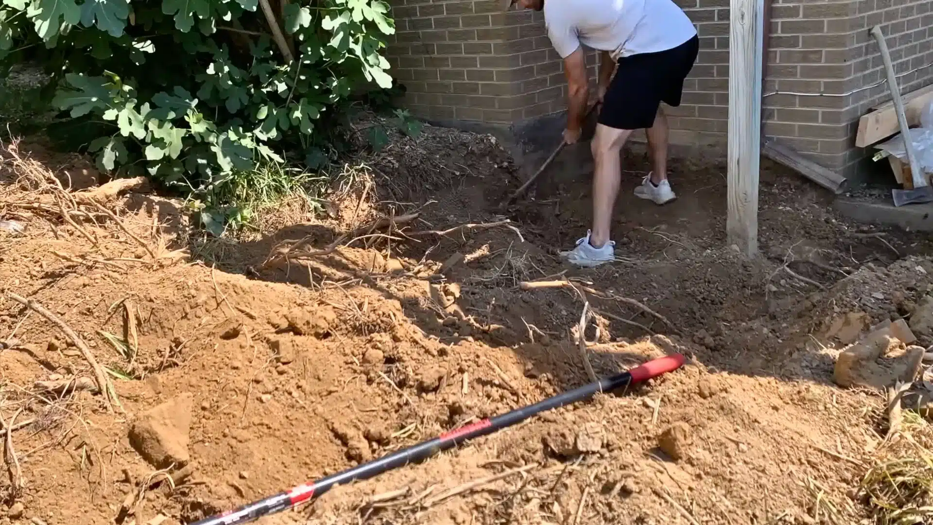 Marking outdoor shower layout and digging deep post holes with gravel added for drainage and wood protection.