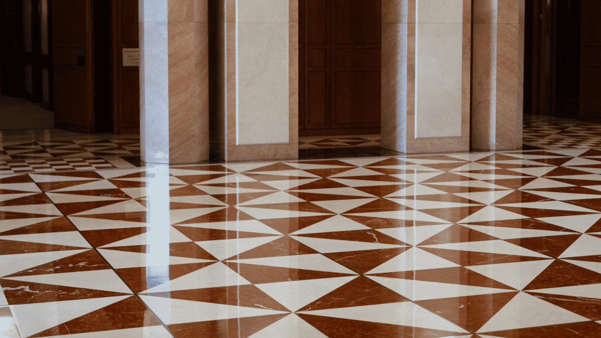 polished geometric tile floor inside a spacious hall with tall columns and reflective surface