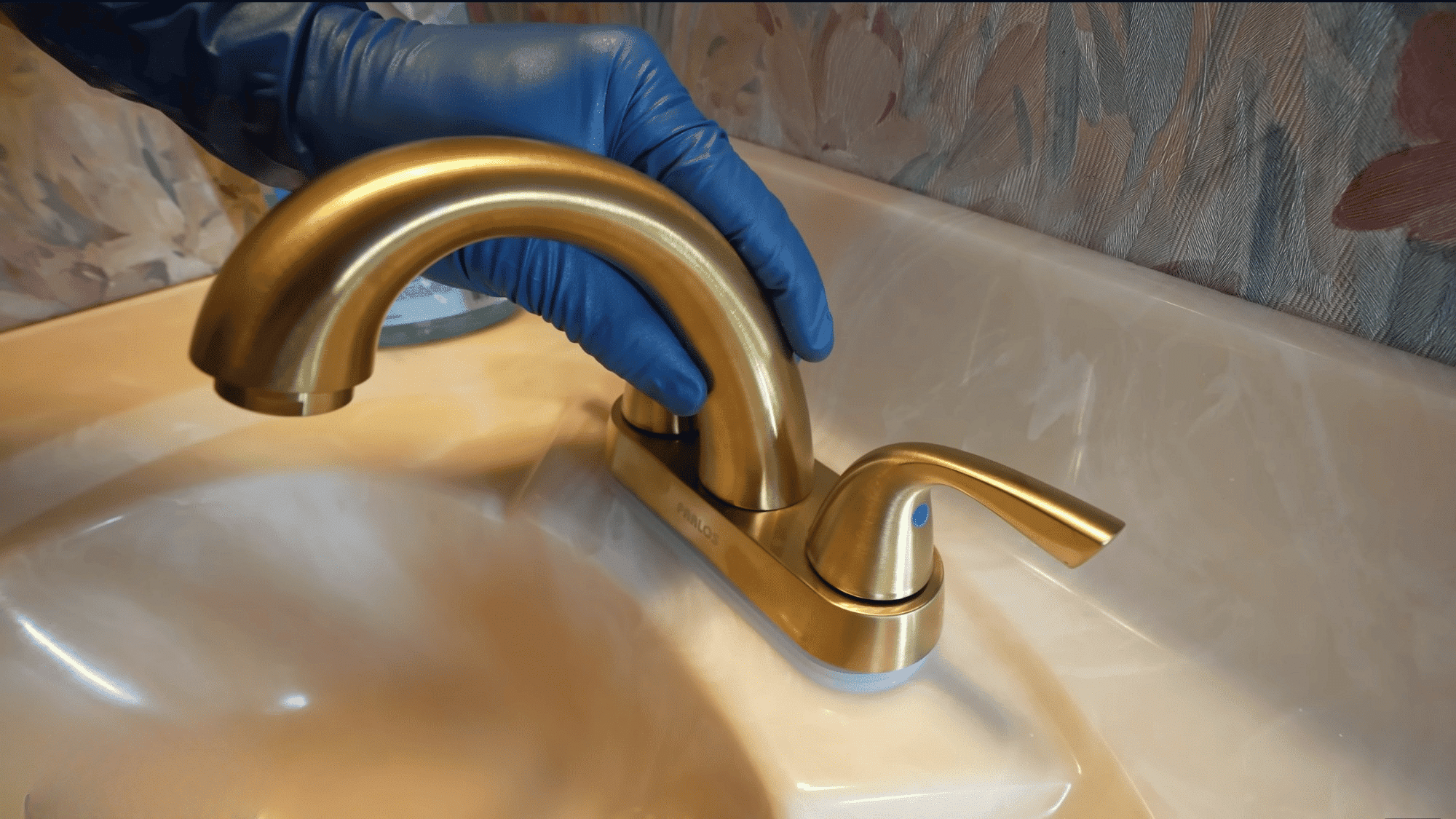 positioning new brushed gold bathroom faucet onto sink deck before securing mounting hardware