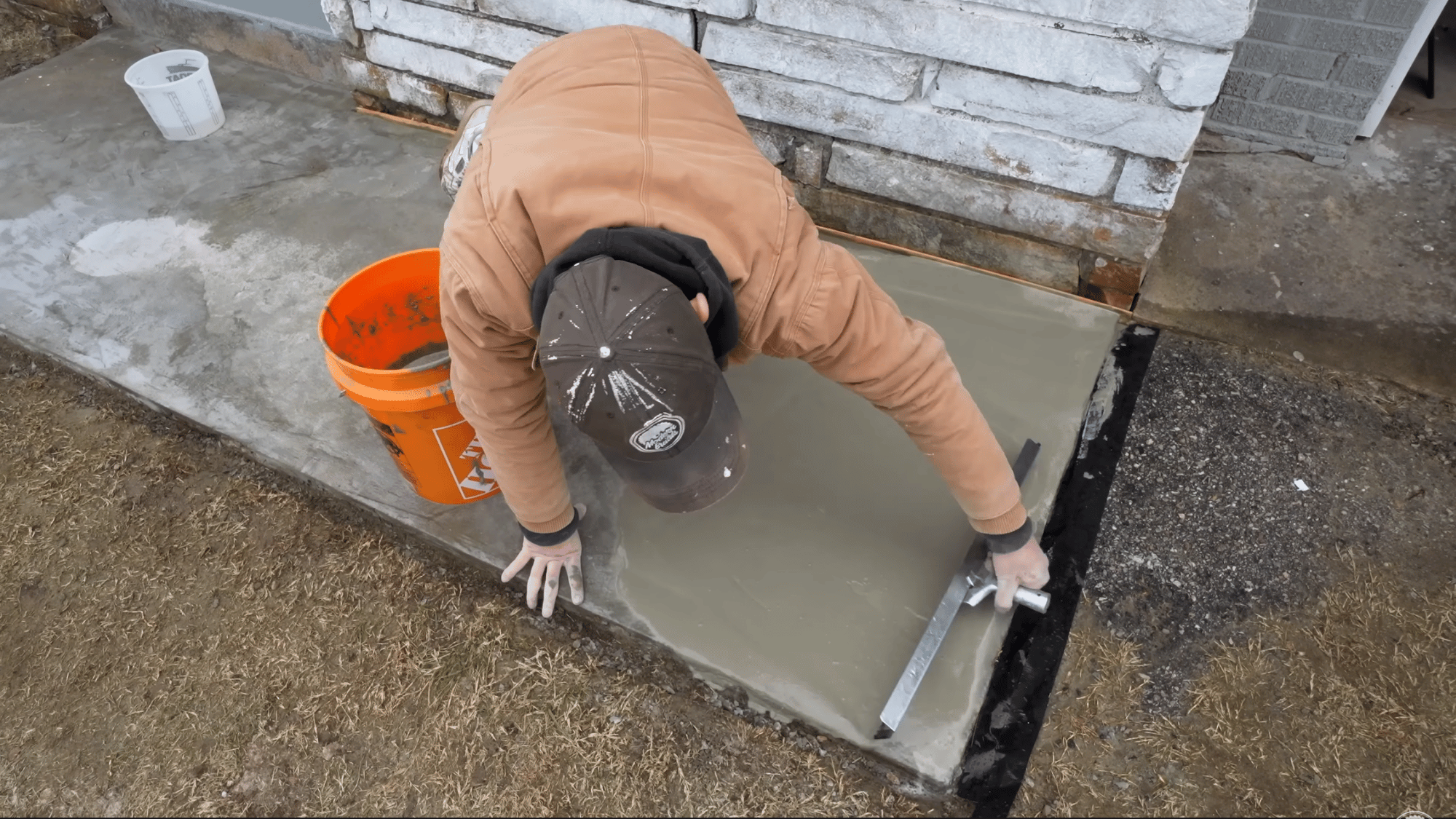 pouring and spreading concrete resurfacer across the slab to cover repairs and create a smooth finish