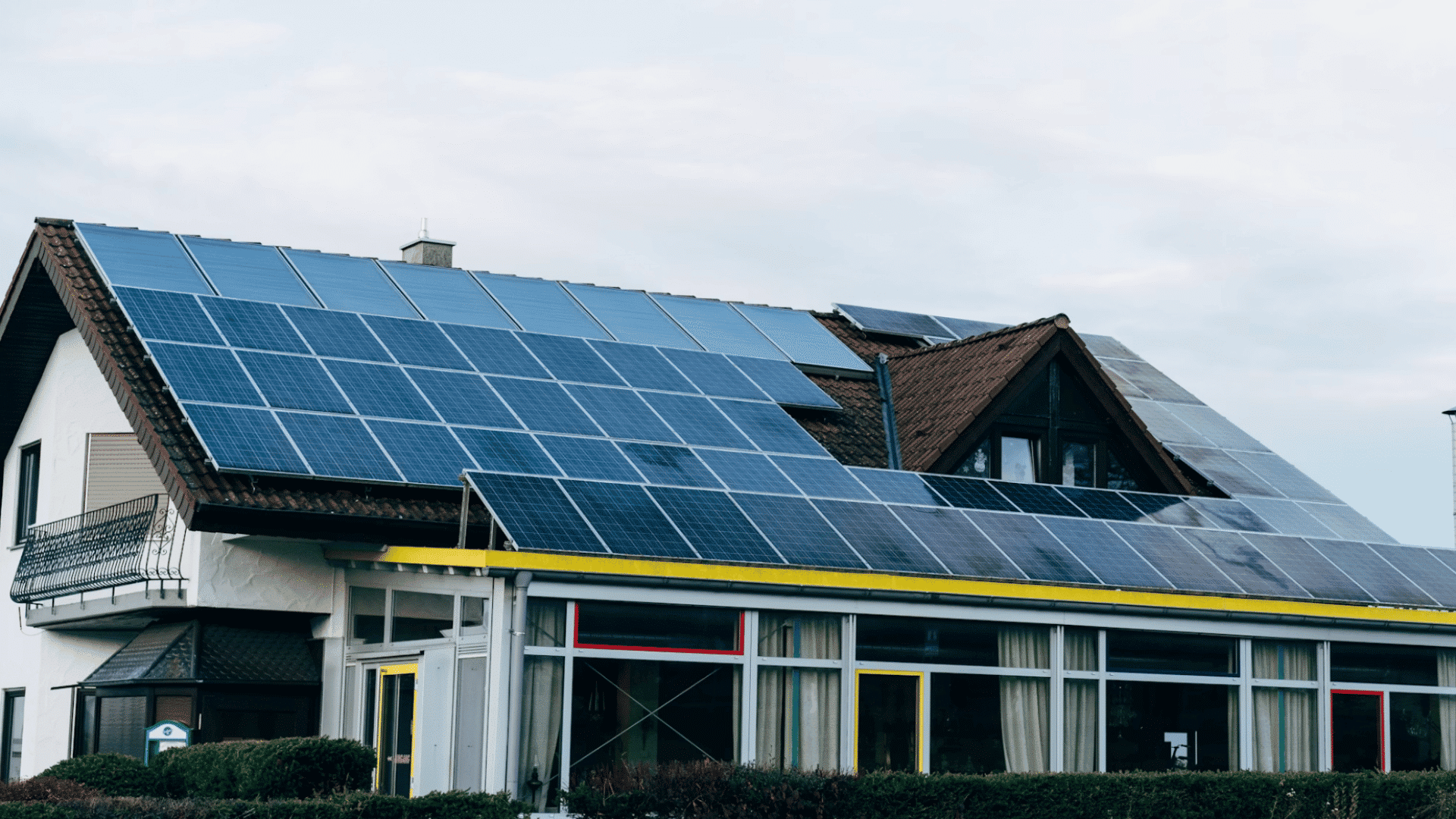 residential building with solar panels covering sloped roofs beneath an overcast sky