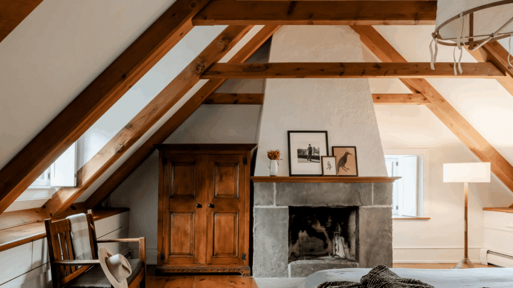 15 Vaulted Ceiling Ideas to Upgrade Your Space Rustic attic bedroom with exposed timber trusses stone fireplace wood flooring and sloped ceiling