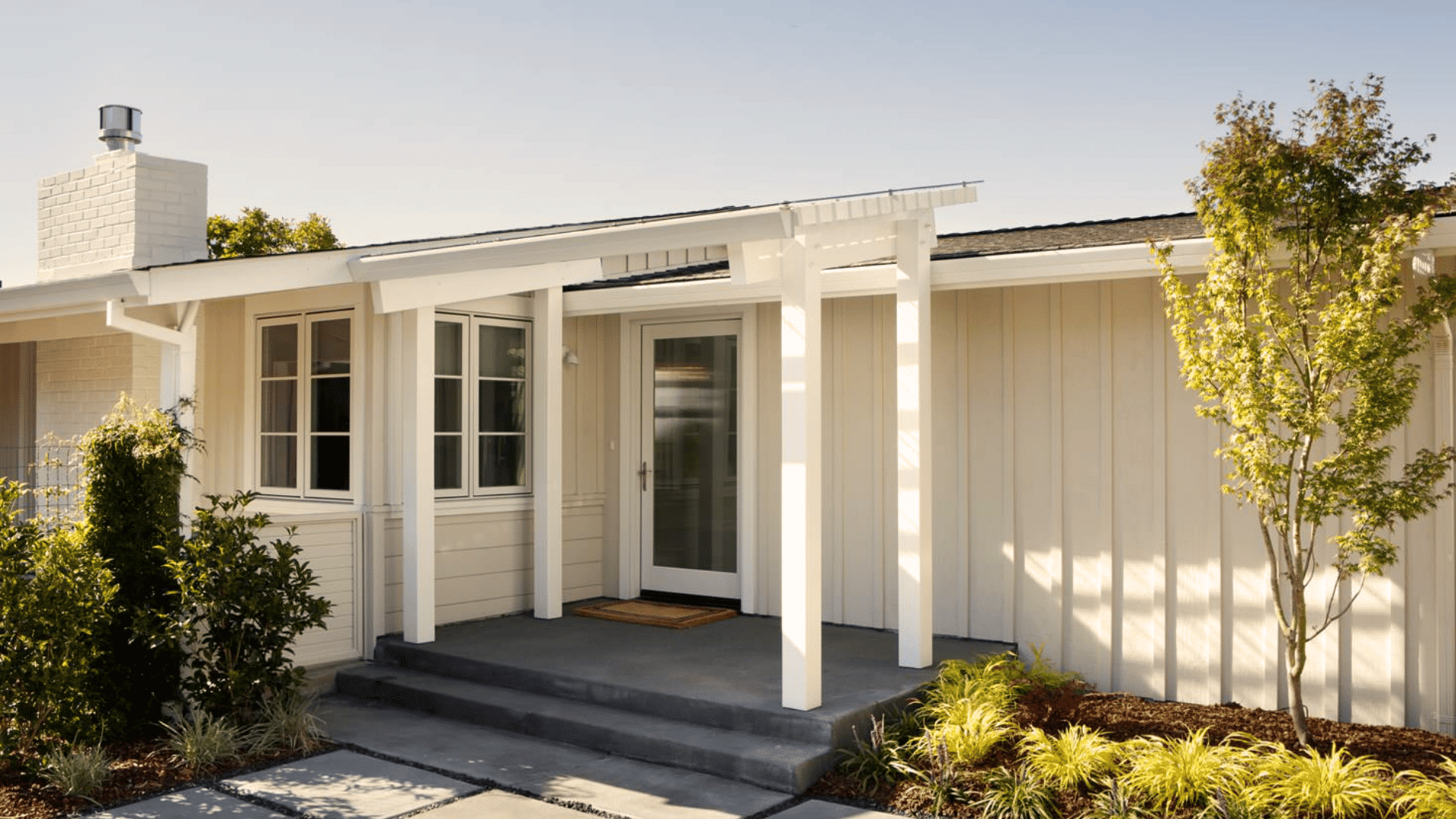 single story ranch style house with covered front porch white siding large windows and simple landscaped yard entrance