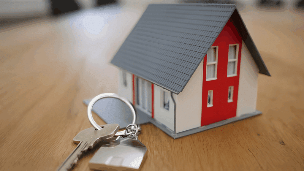 small model house with keys on a wooden table symbolizing home ownership