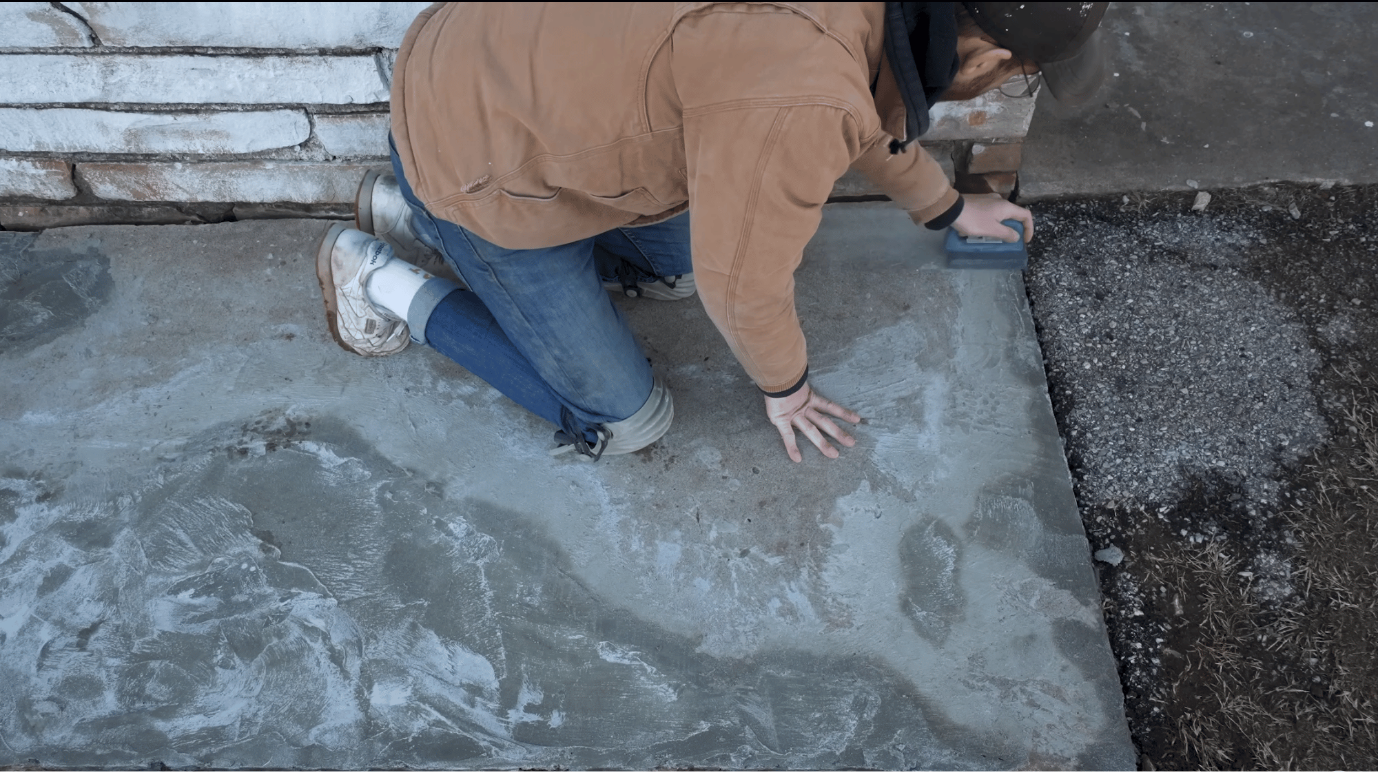 smoothing repaired concrete with a honing block to remove high spots before resurfacing the slab