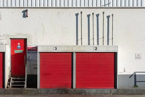 Storage Locker Size Guide: How to Pick the Perfect Fit Red garage doors and fire exit on industrial white brick building in sunlight