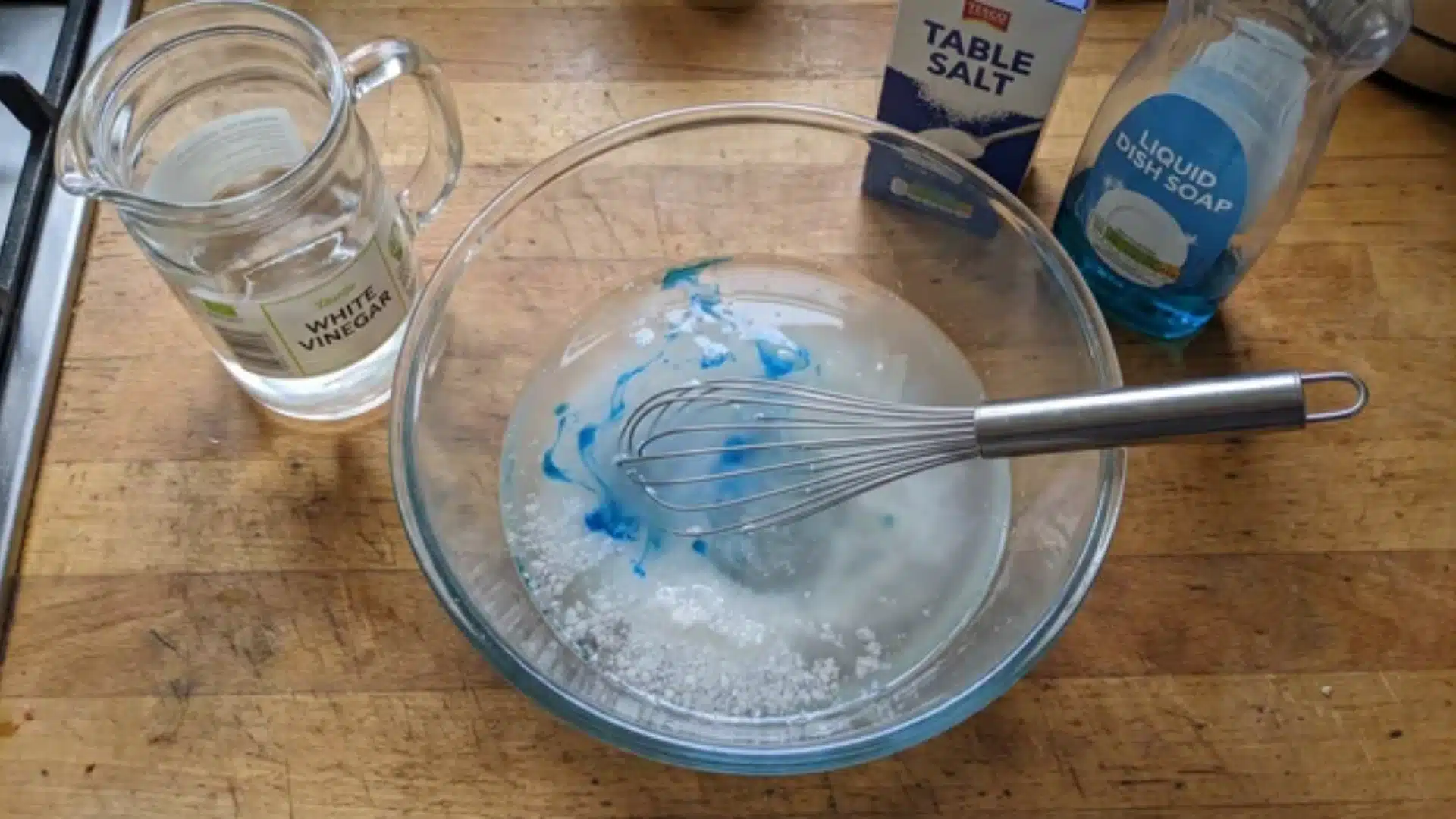 vinegar, salt, and dish soap measured in a container on a kitchen counter