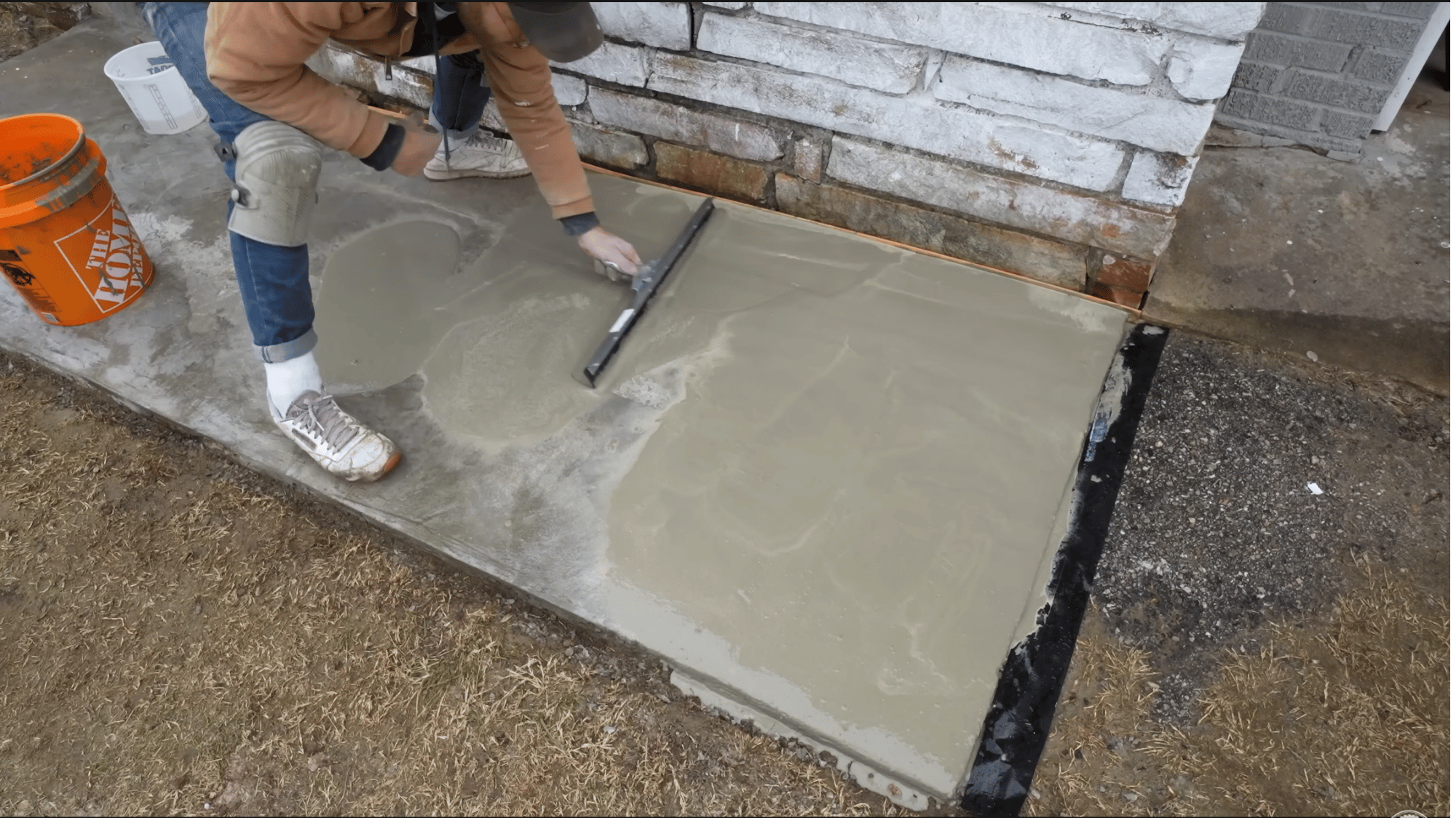 using a squeegee to distribute concrete resurfacer evenly across the surface and fill low spots