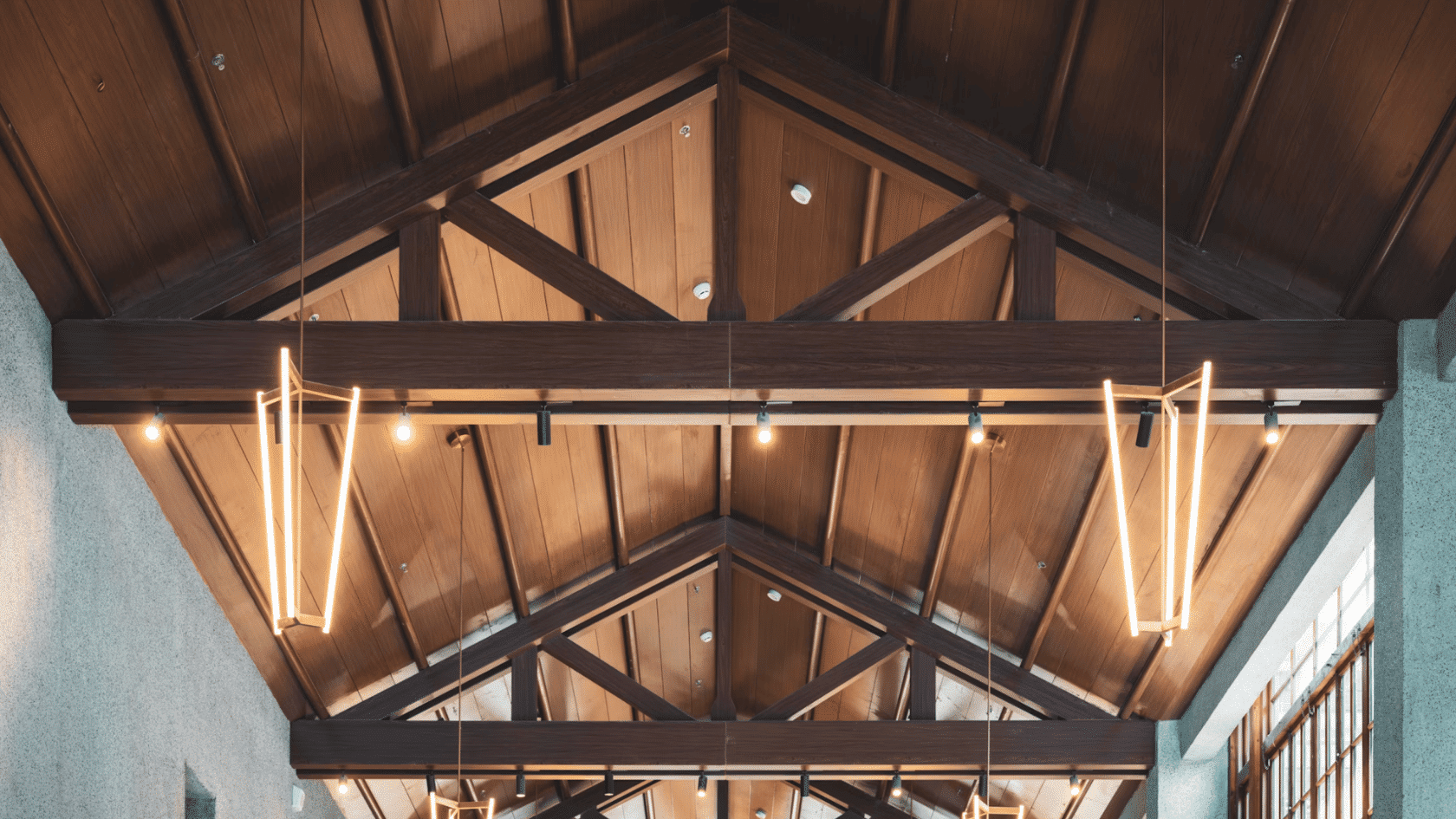 Vaulted wooden ceiling with exposed beams, warm pendant lights, and modern rustic architectural design indoors.