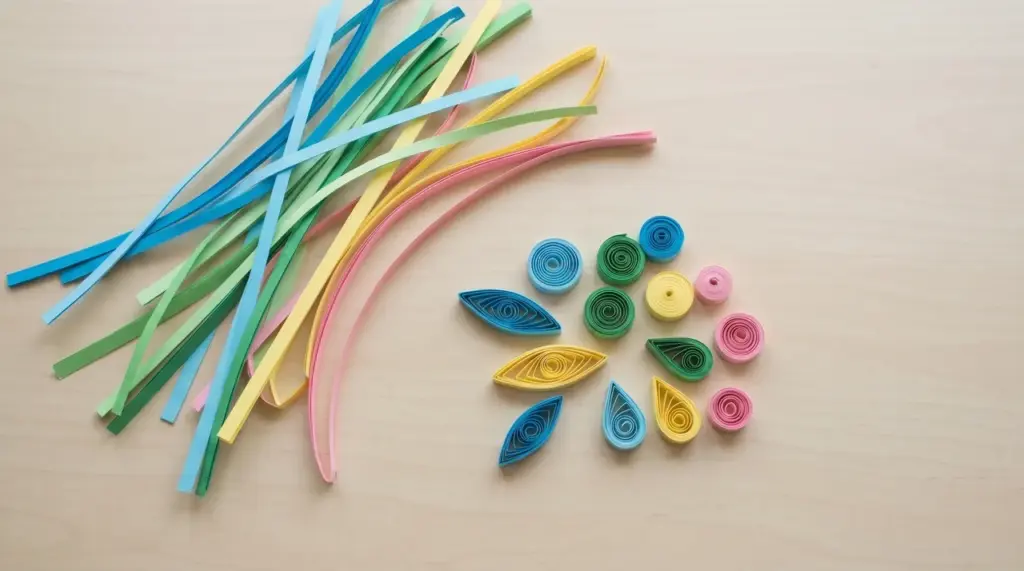 Colorful quilling paper strips and shaped paper coils arranged on a flat white surface