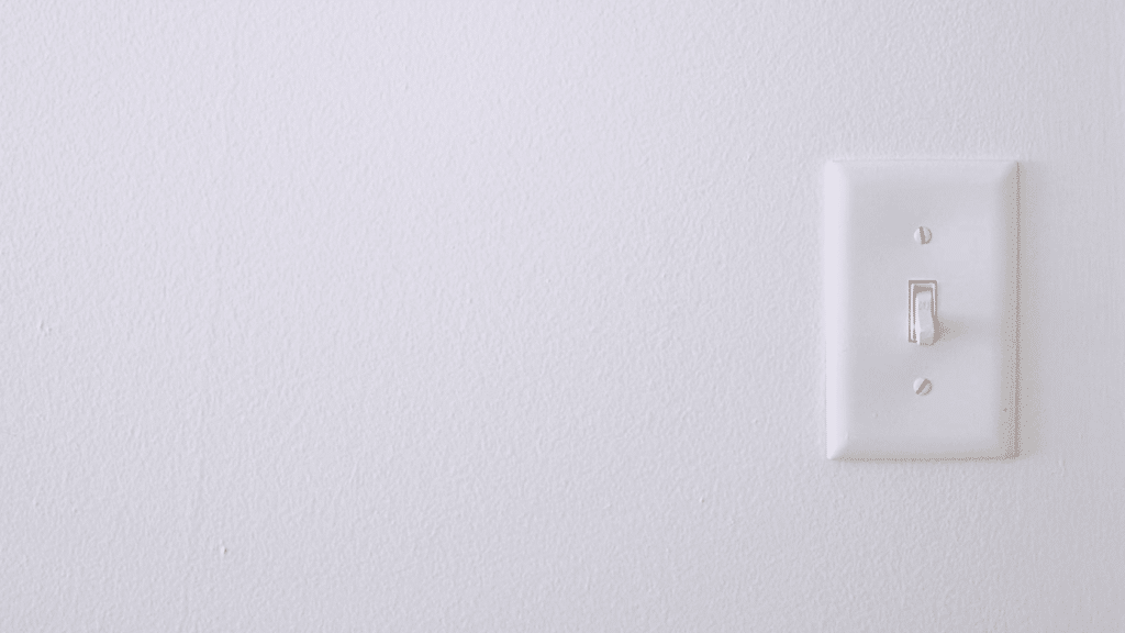 white light switch mounted on a plain textured wall with ample empty space creating a minimal indoor scene