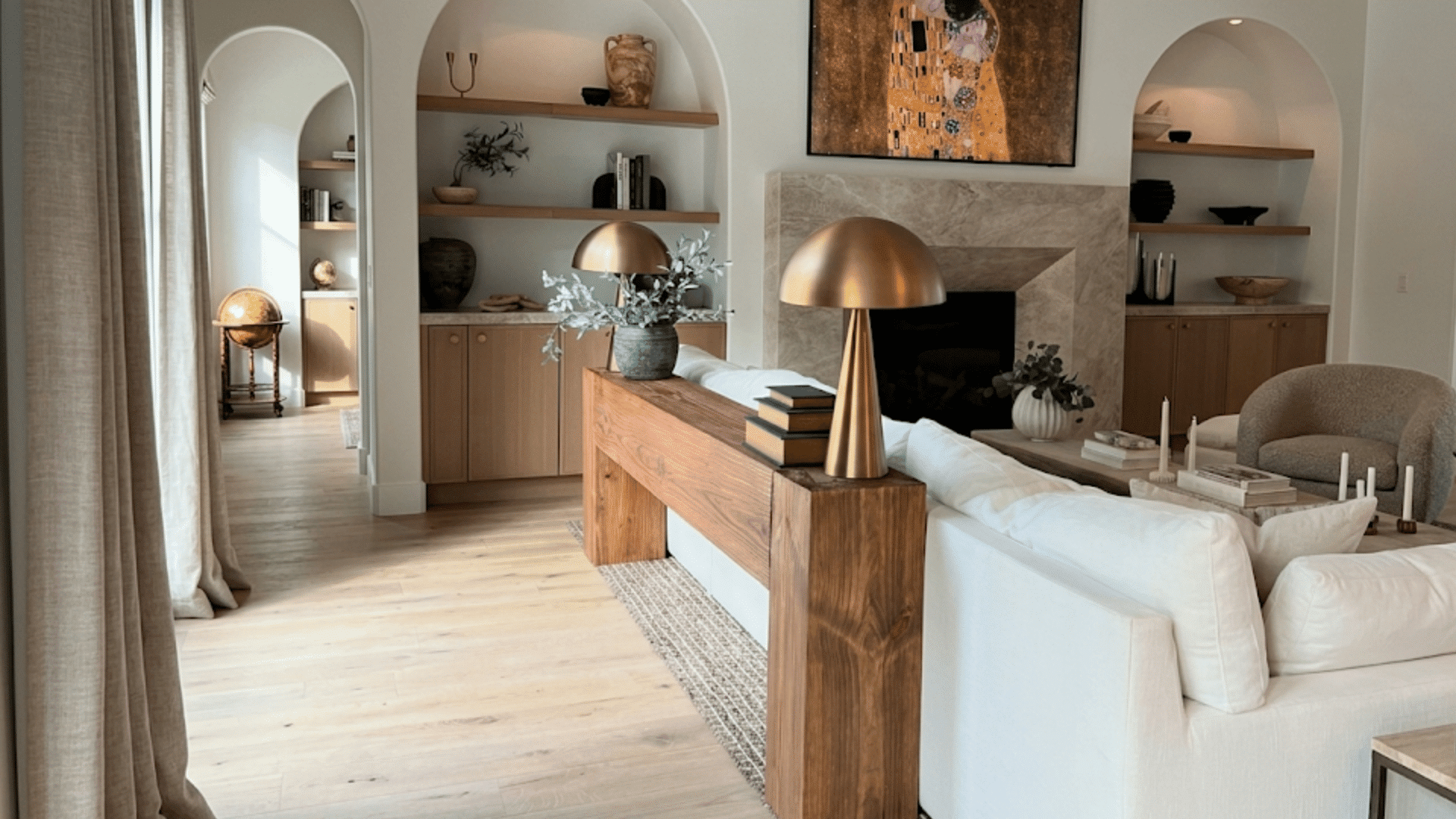 wood console table behind a white sofa with lamps and decor in a bright modern living room interior
