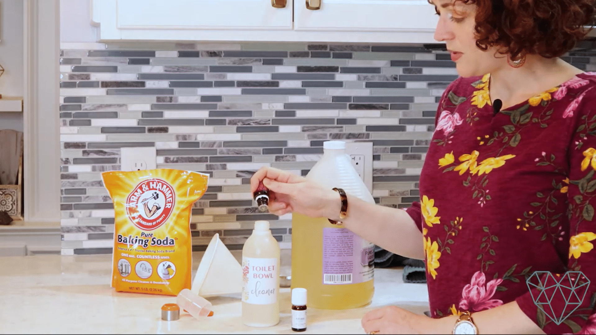 adding essential oil drops to a homemade diy toilet bowl cleaner with castile soap baking soda and reusable bottle on a kitchen counter