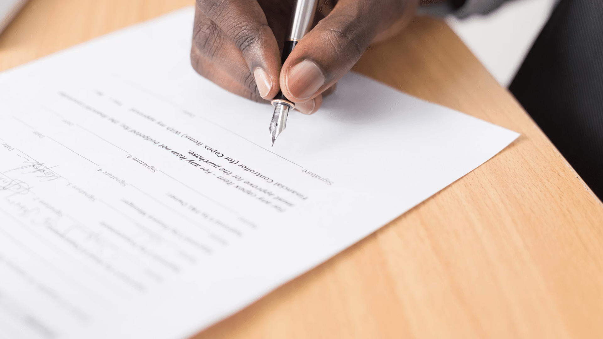 close up of hands signing lease termination documents with house keys and important rental papers nearby